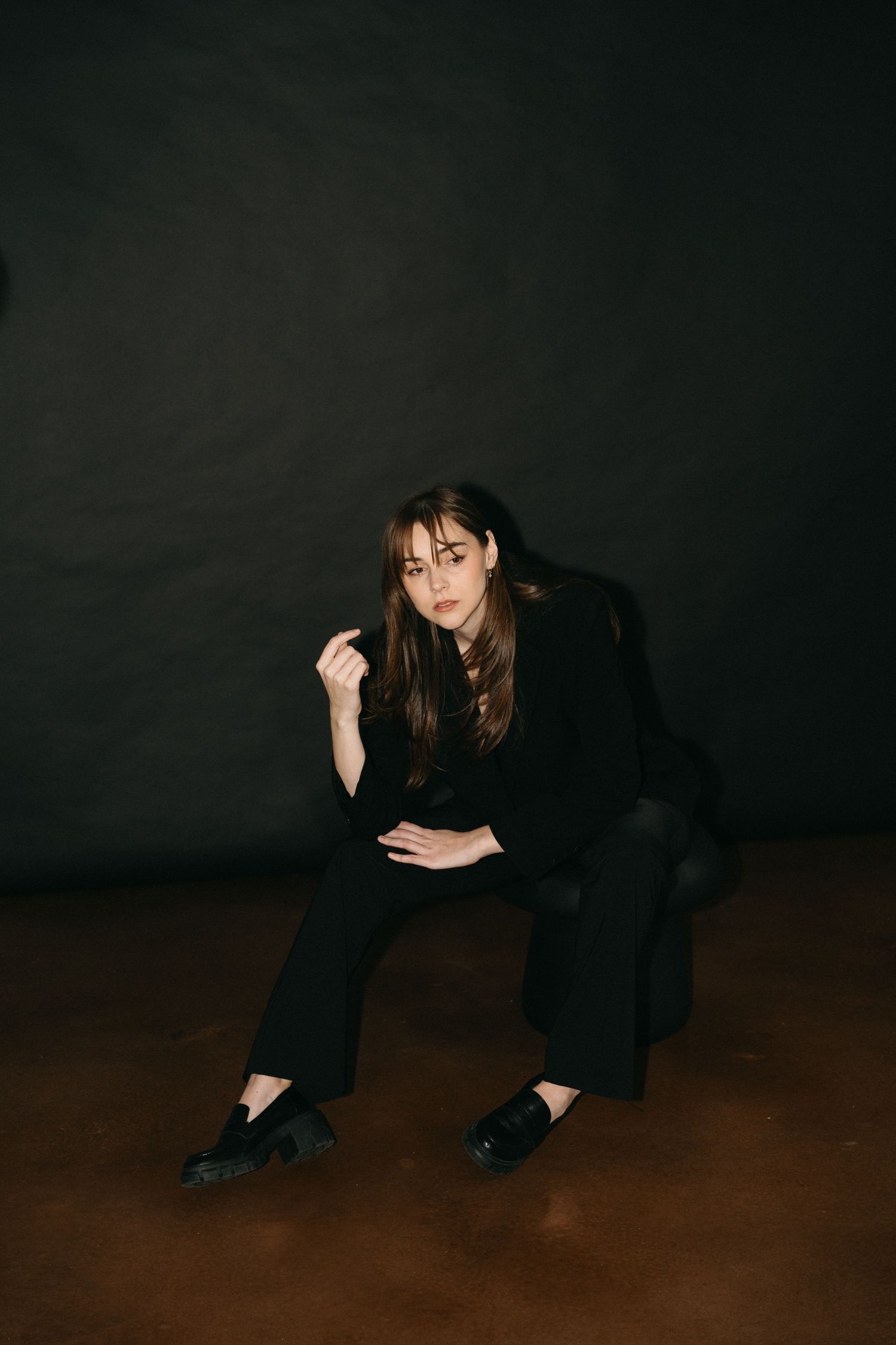 A sequence of four dark moody photos showing a person in black clothing crouching and moving on a dark wooden floor in Halifax, Nova Scotia.