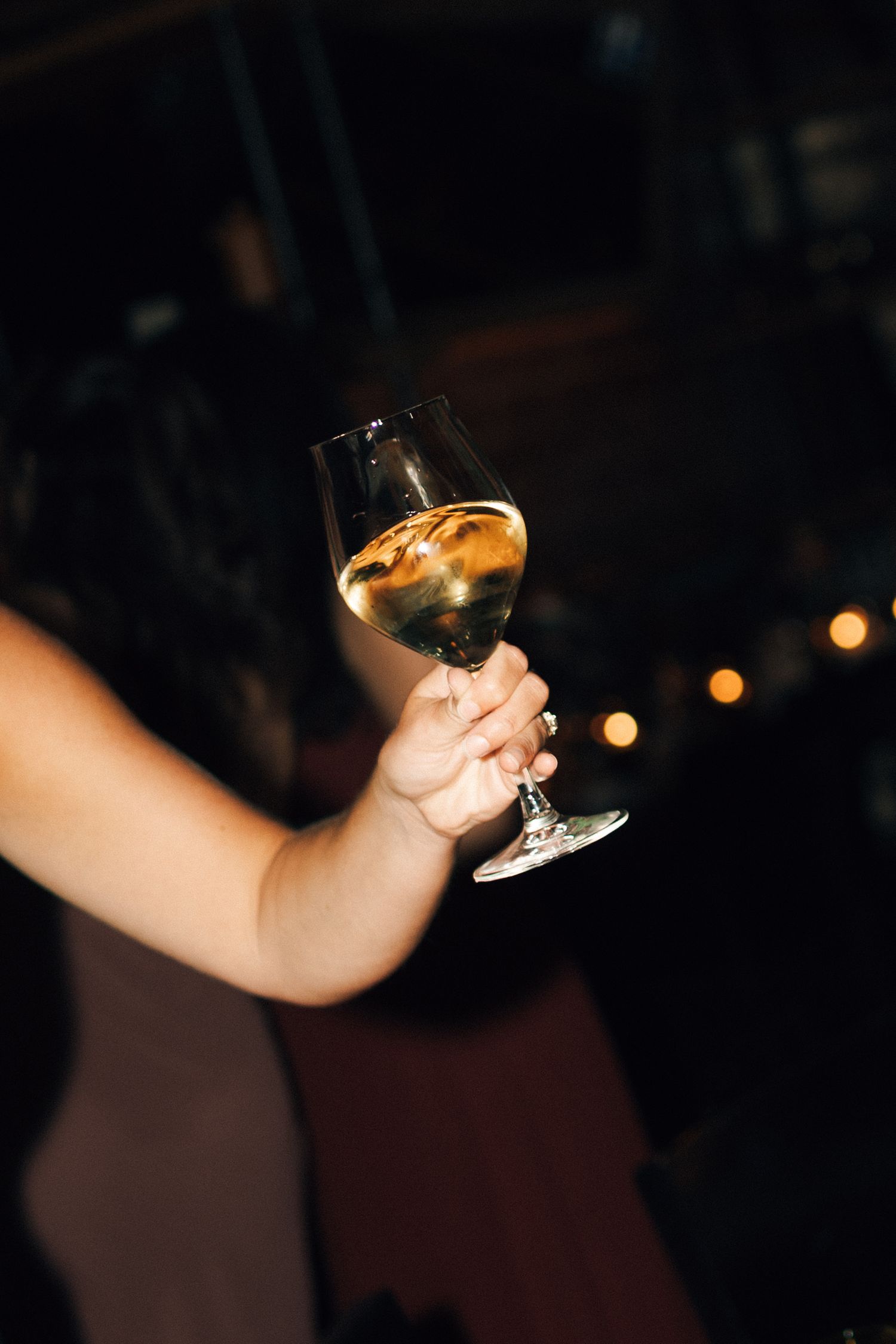 Hand holding a martini glass with cocktail against dark background in sequence of four similar photos in Halifax, Nova Scotia.