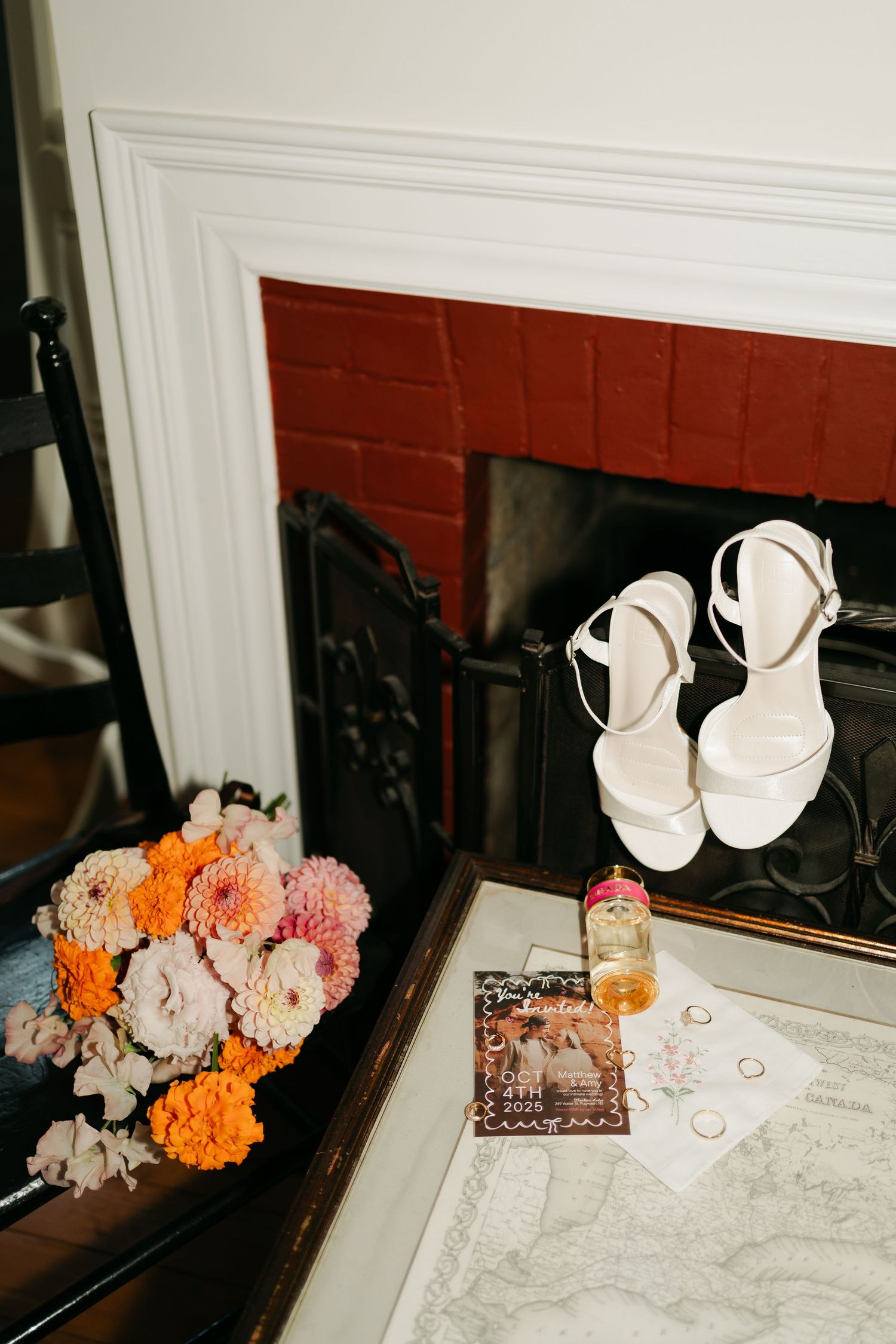 Wedding details featuring white heels, orange and pink floral arrangements, and decor items on a marble surface in Nova Scotia.