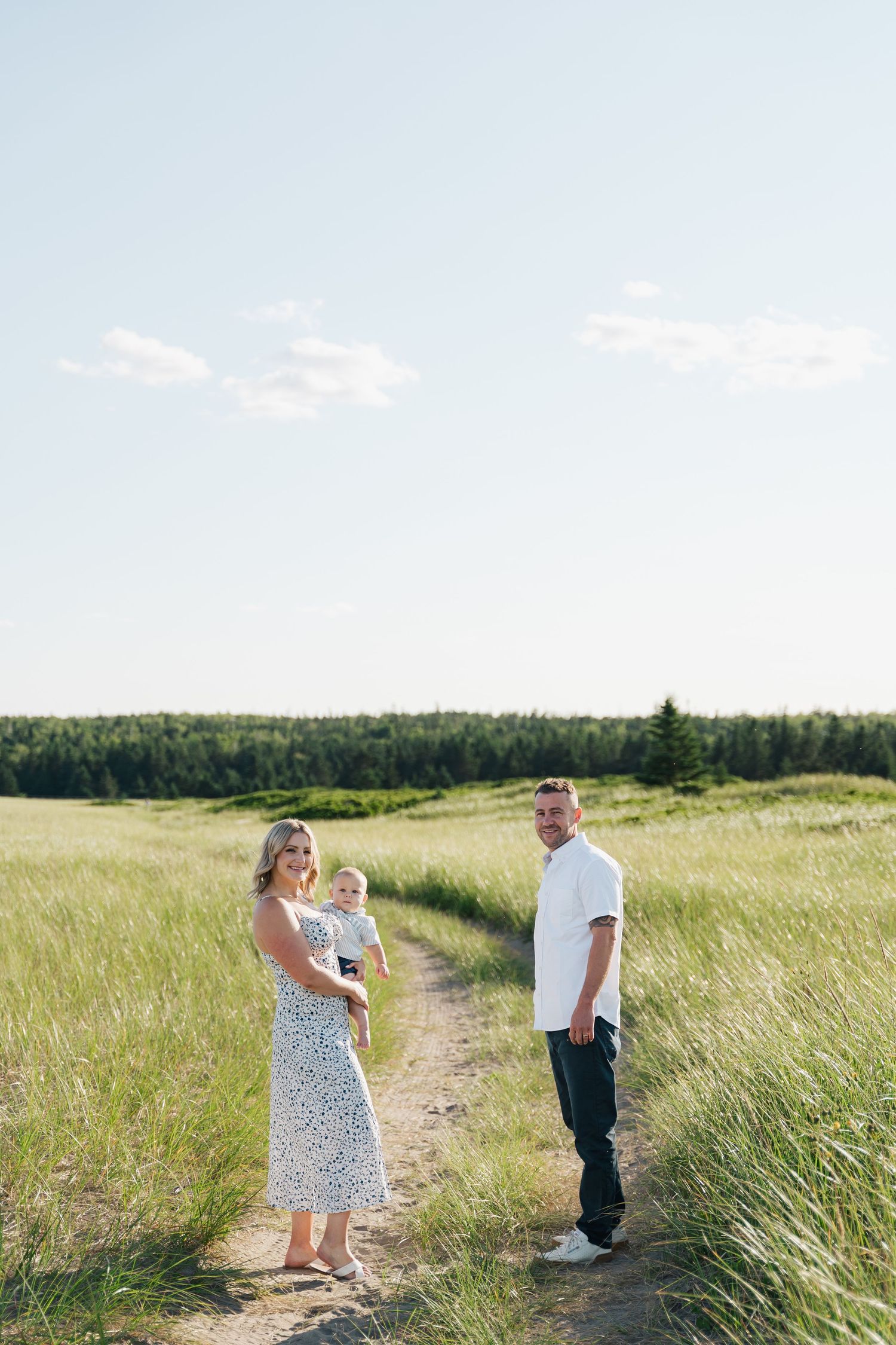 People walk along a winding path through tall grass meadows on a sunny summer day in Halifax, Nova Scotia.