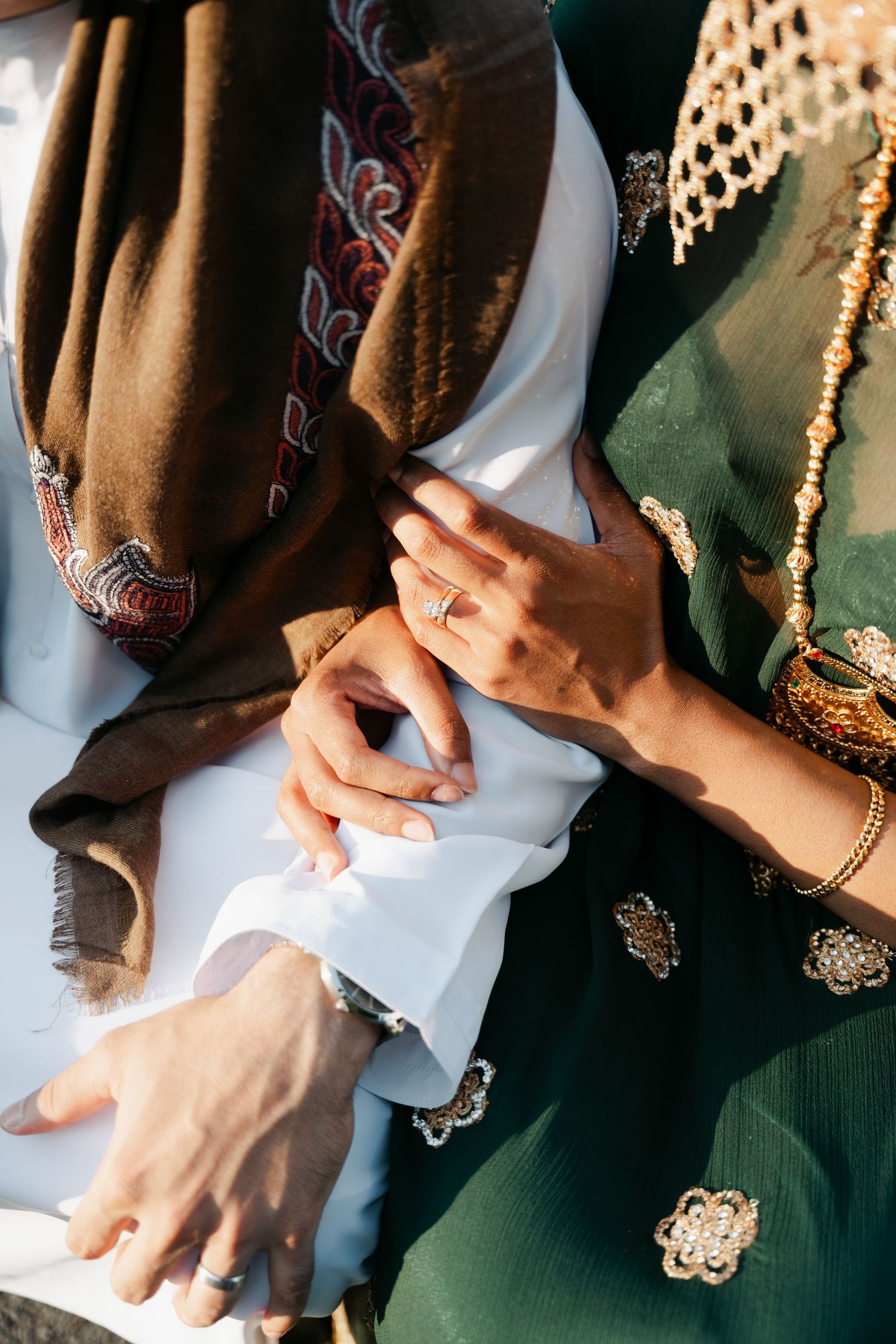 Close-up view of hands wearing traditional South Asian wedding attire with gold jewelry and embroidered fabrics in Halifax, Nova Scotia.