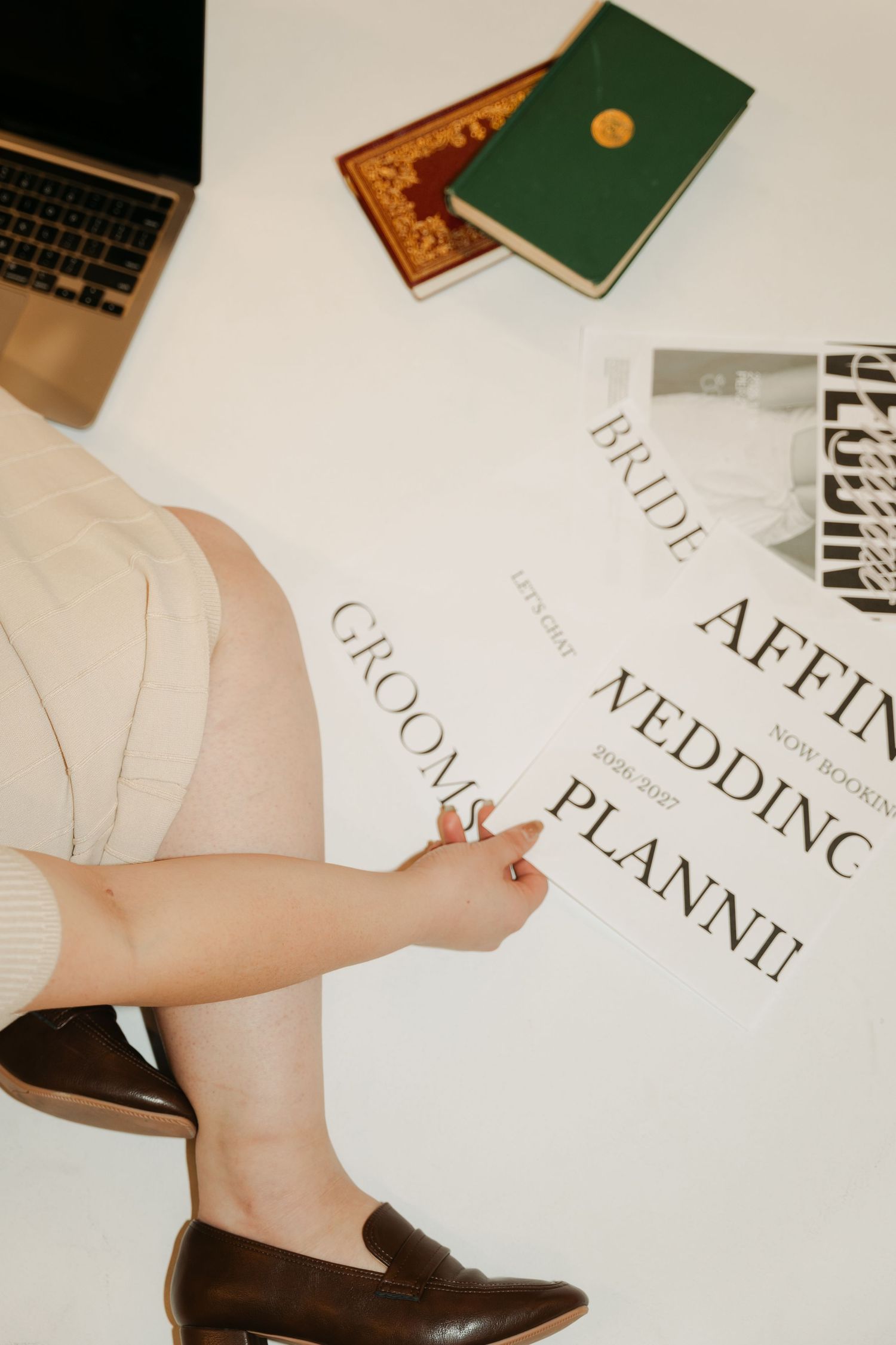 Wedding planner paperwork and brown leather loafer shown with laptop and books on white surface in Halifax, Nova Scotia.