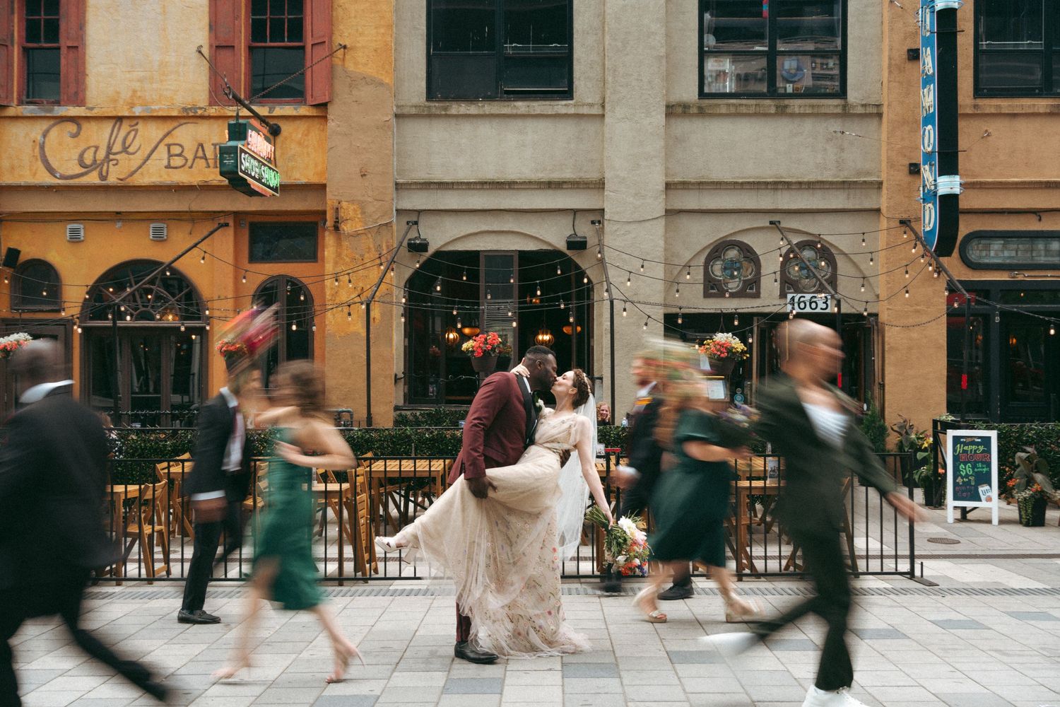 Motion-blurred pedestrians walk past a beige stone building with red windows in an urban setting in Halifax, Nova Scotia.