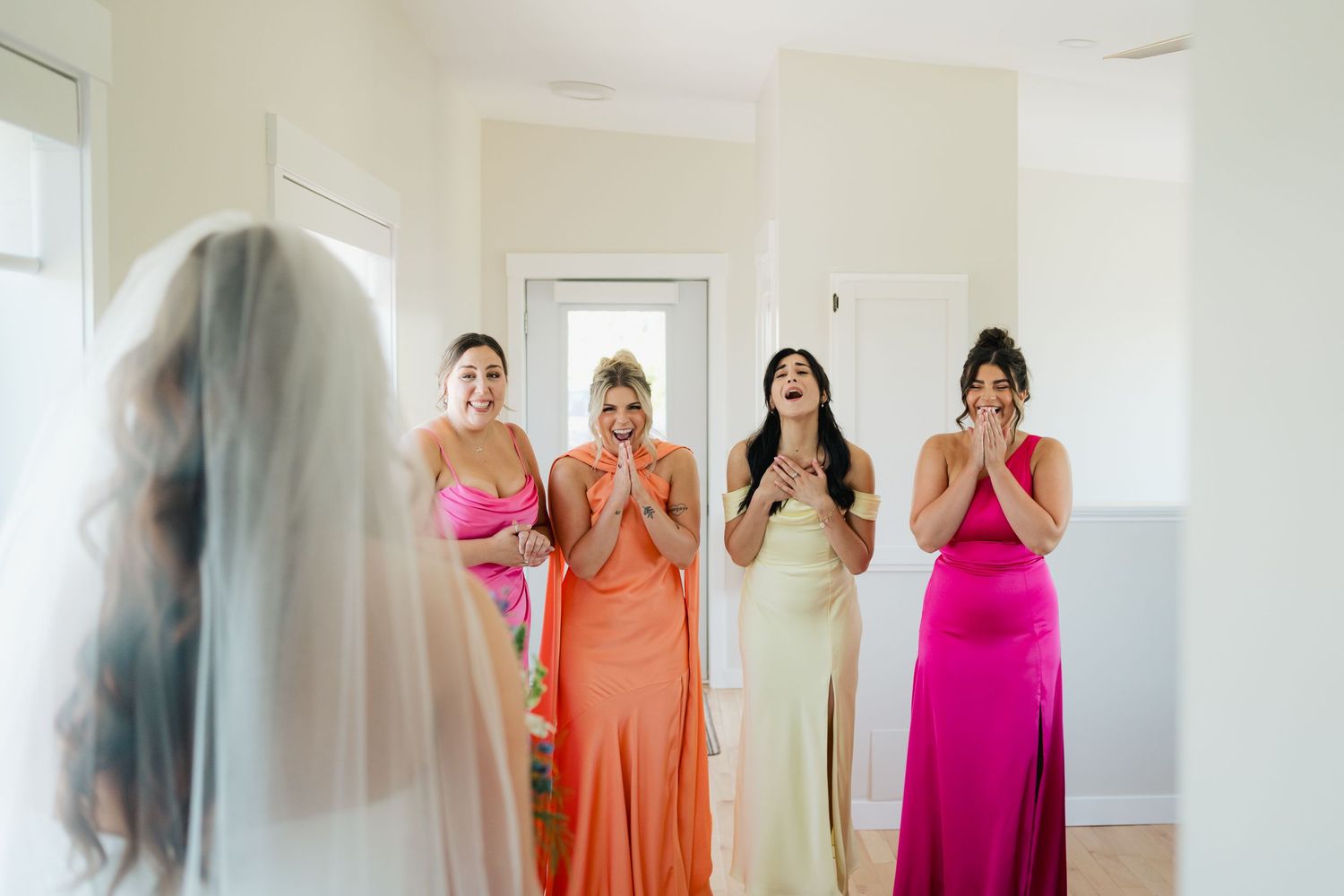 People in colorful bridesmaid dresses prepare for a wedding in a bright white room in Halifax, Nova Scotia.