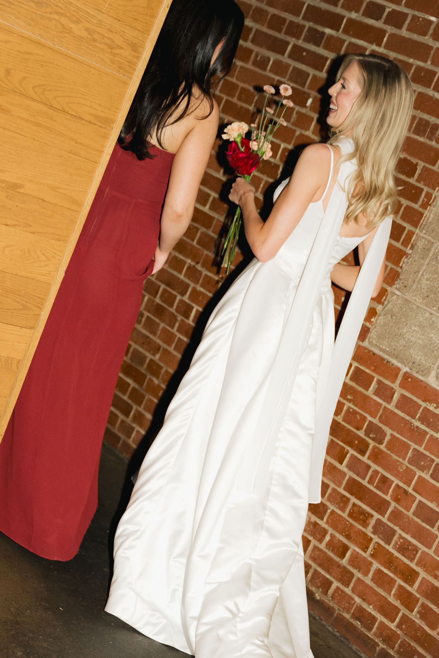 Wedding celebration in front of a brick wall with white and red attire in Halifax, Nova Scotia.
