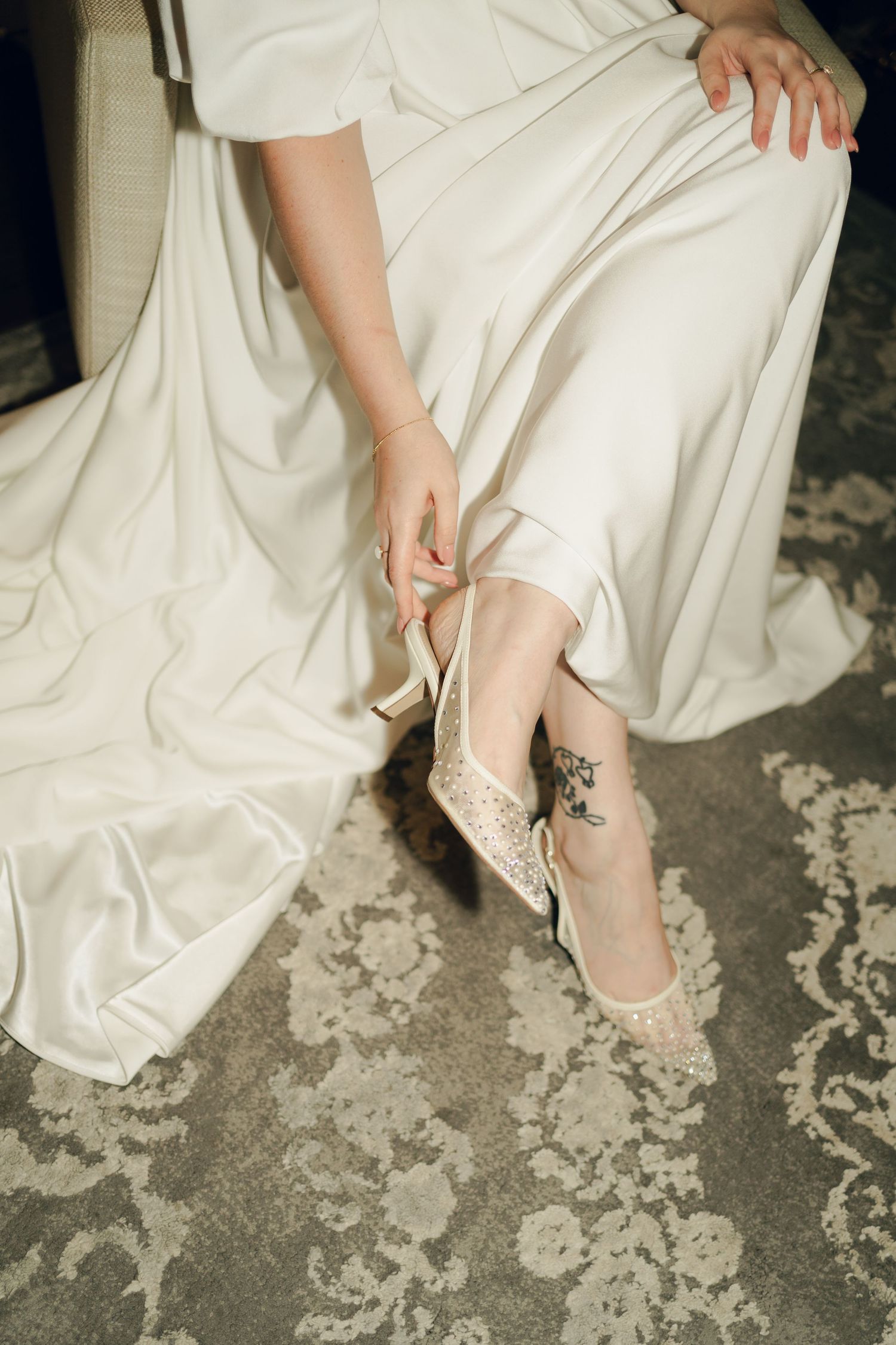 Close-up of bride's feet in delicate lace wedding shoes against white dress and textured floor at Lord Nelson Hotel, Halifax, Nova Scotia.