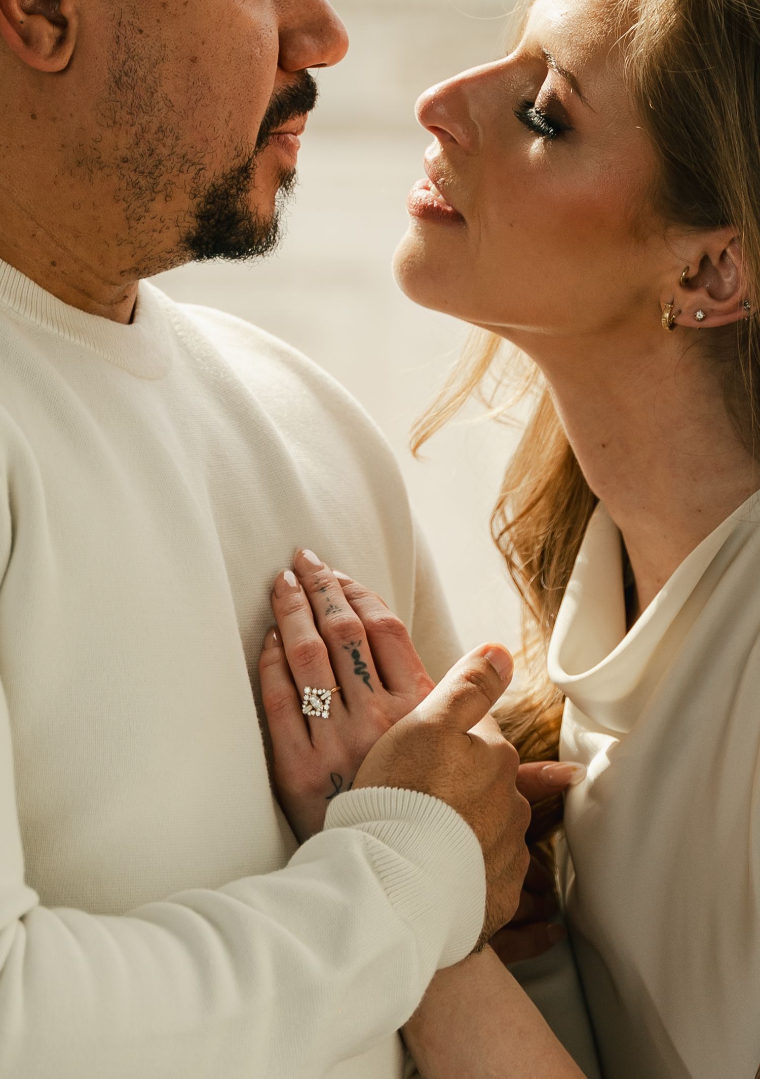 Intimate close-up shots of a couple in white clothing sharing tender moments together in warm sunlight.