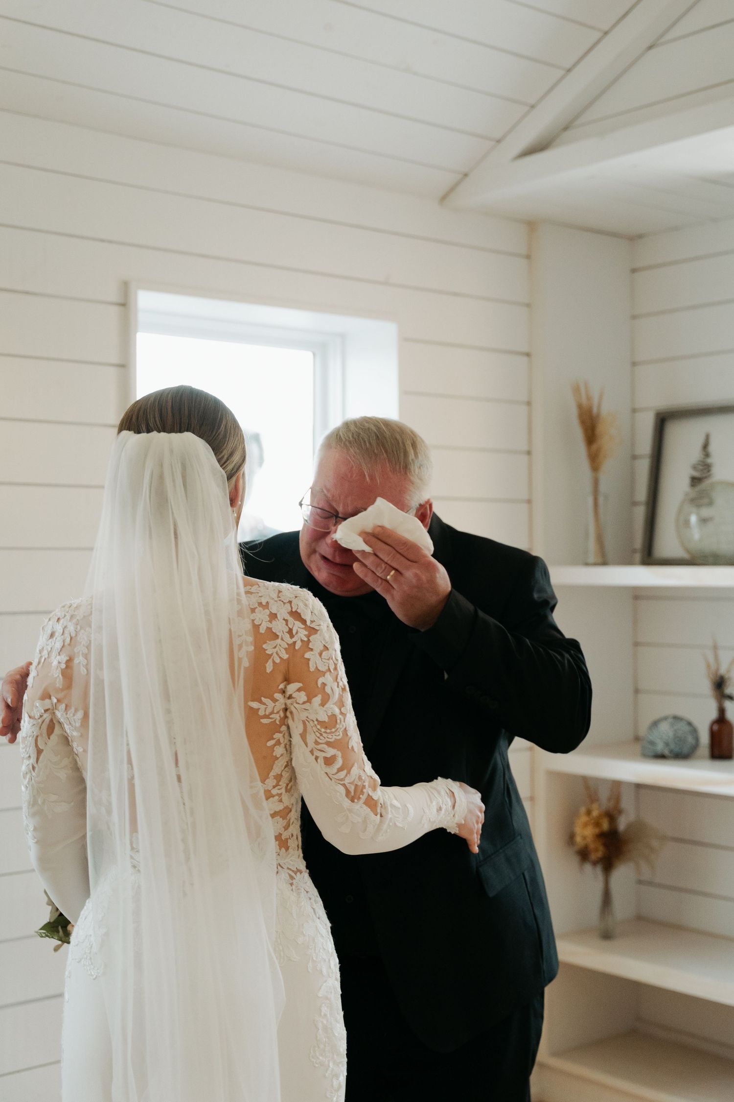 A couple shares an intimate moment in a bright white room with shiplap walls at Lightfoot & Wolfville.