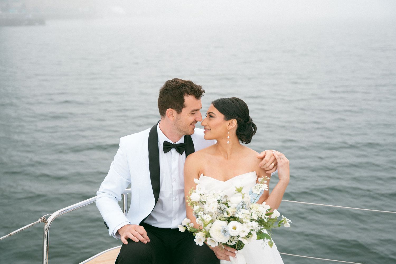 Elegant wedding couple shares romantic moments by the ocean with white floral bouquet and formal attire in Halifax, Nova Scotia.