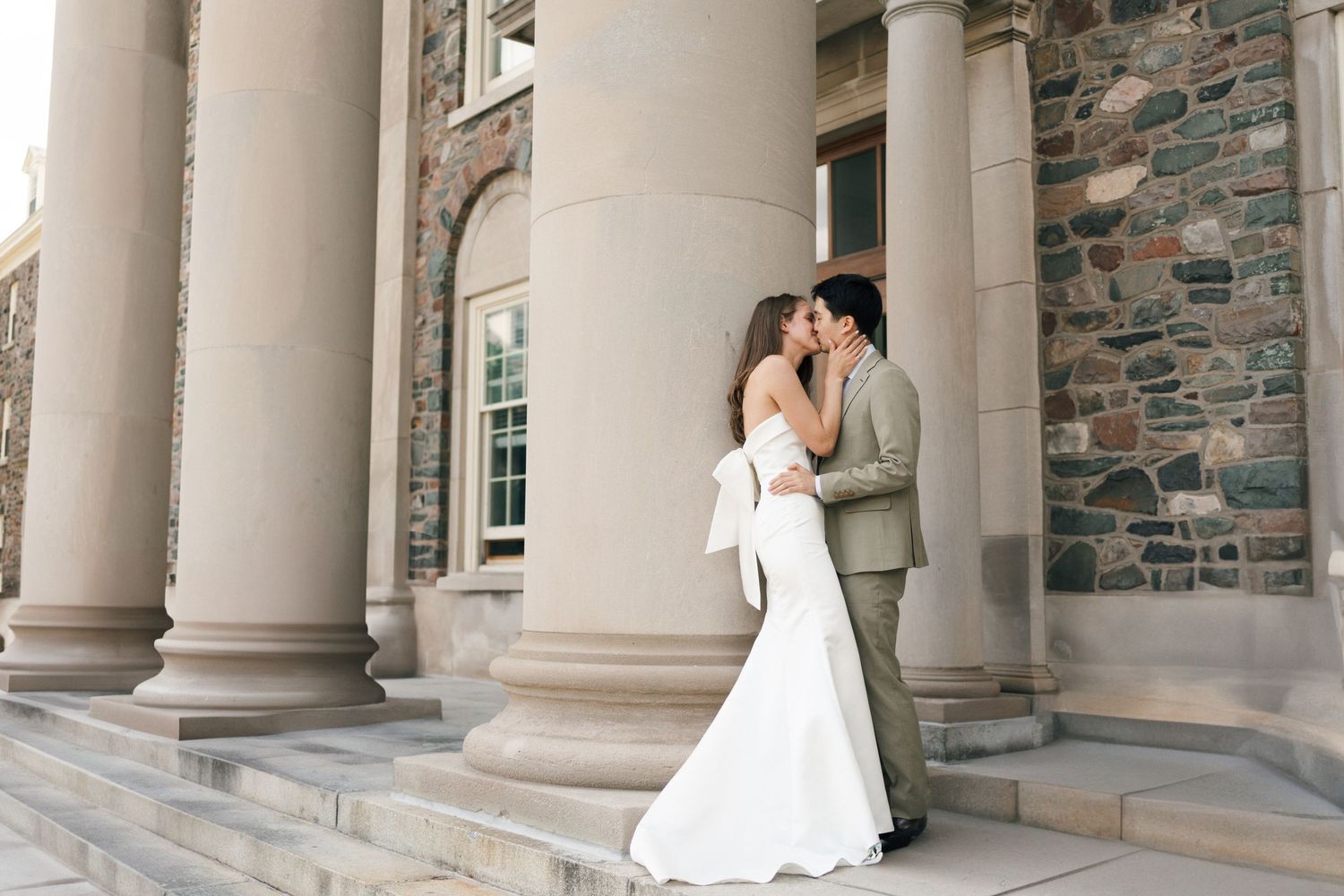 A couple shares a romantic moment under elegant stone columns during their wedding photo session in Halifax, Nova Scotia.