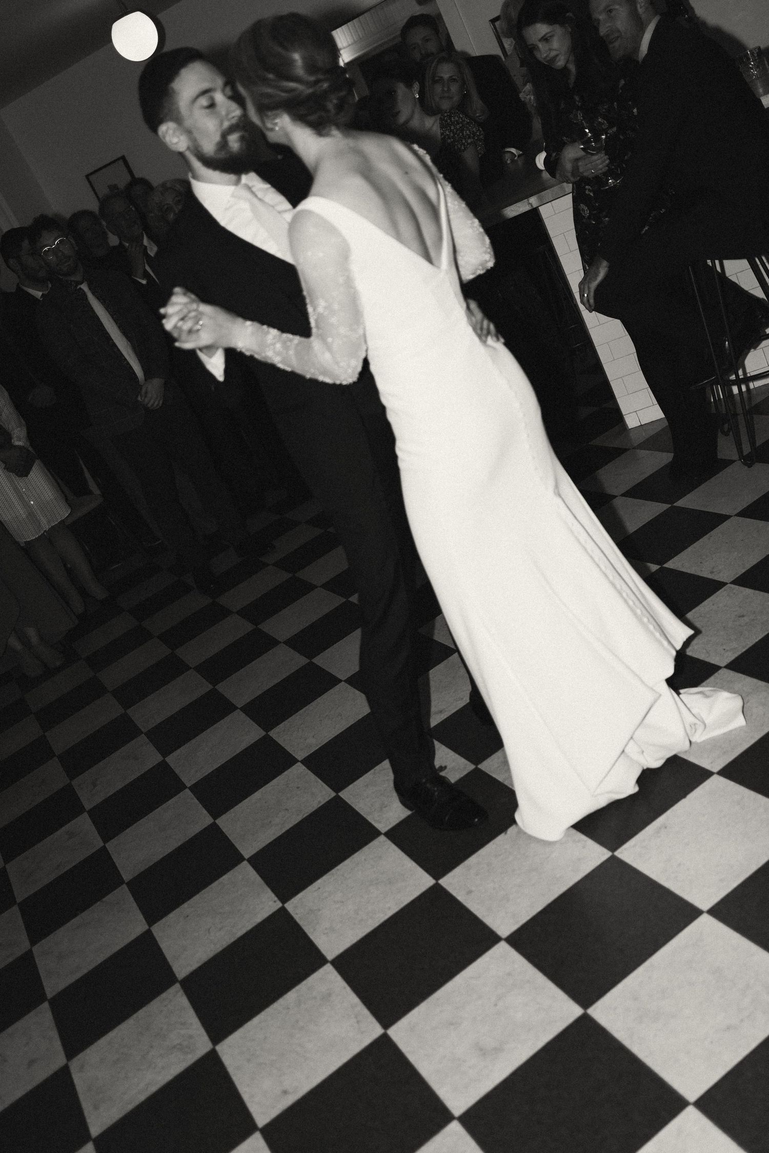 A couple performs their first dance on a black and white checkered floor at their wedding reception in Nova Scotia.
