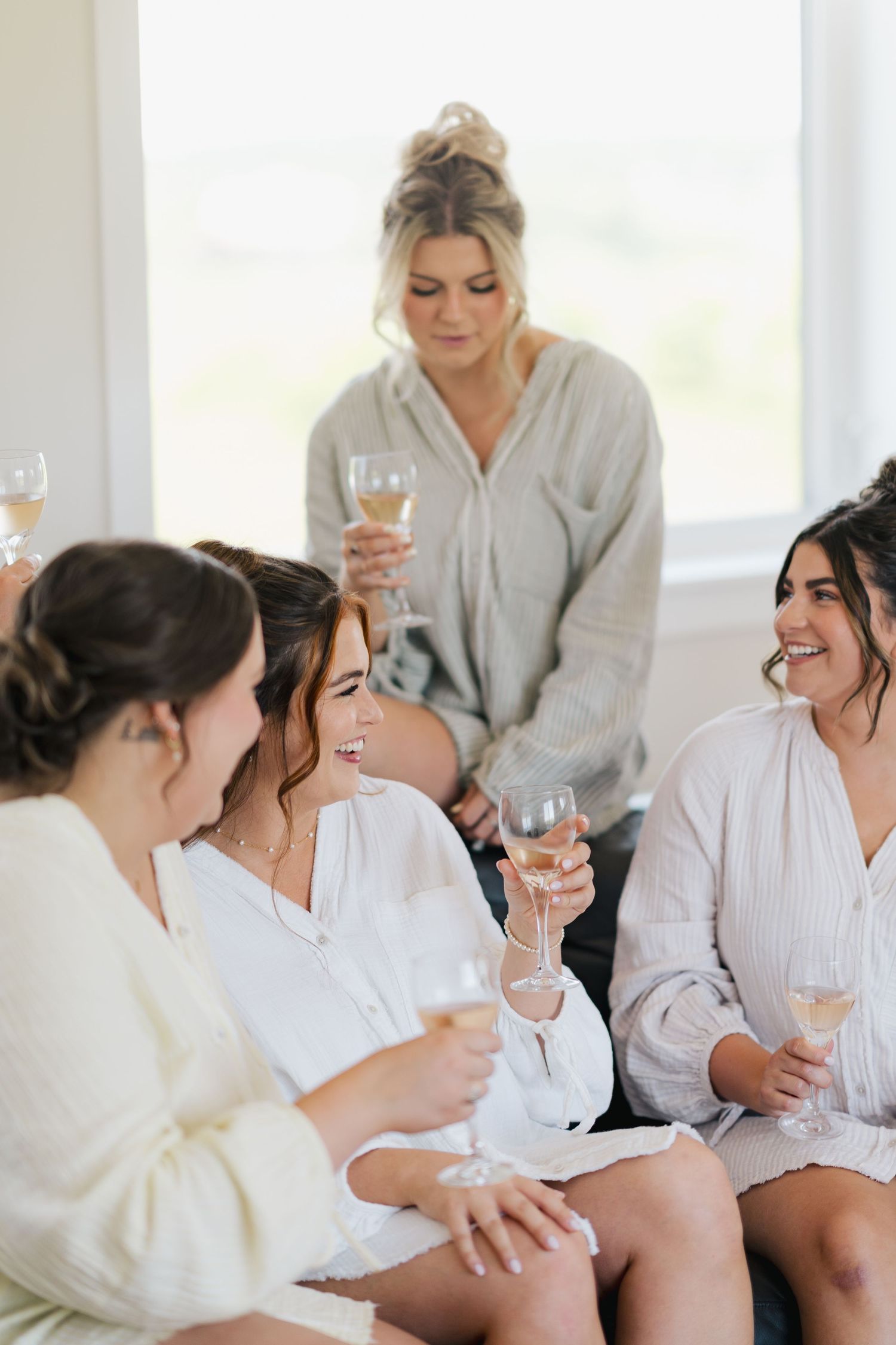 Group of people in white robes sharing drinks and laughs during a relaxing spa day celebration in Halifax, Nova Scotia.