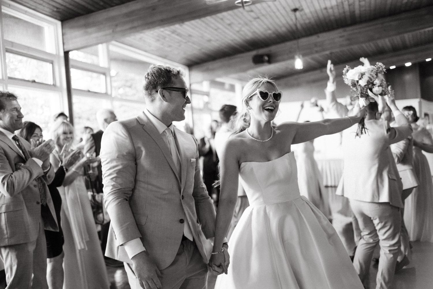 Wedding reception guests dancing and celebrating in a venue with wooden ceiling beams in Halifax, Nova Scotia.