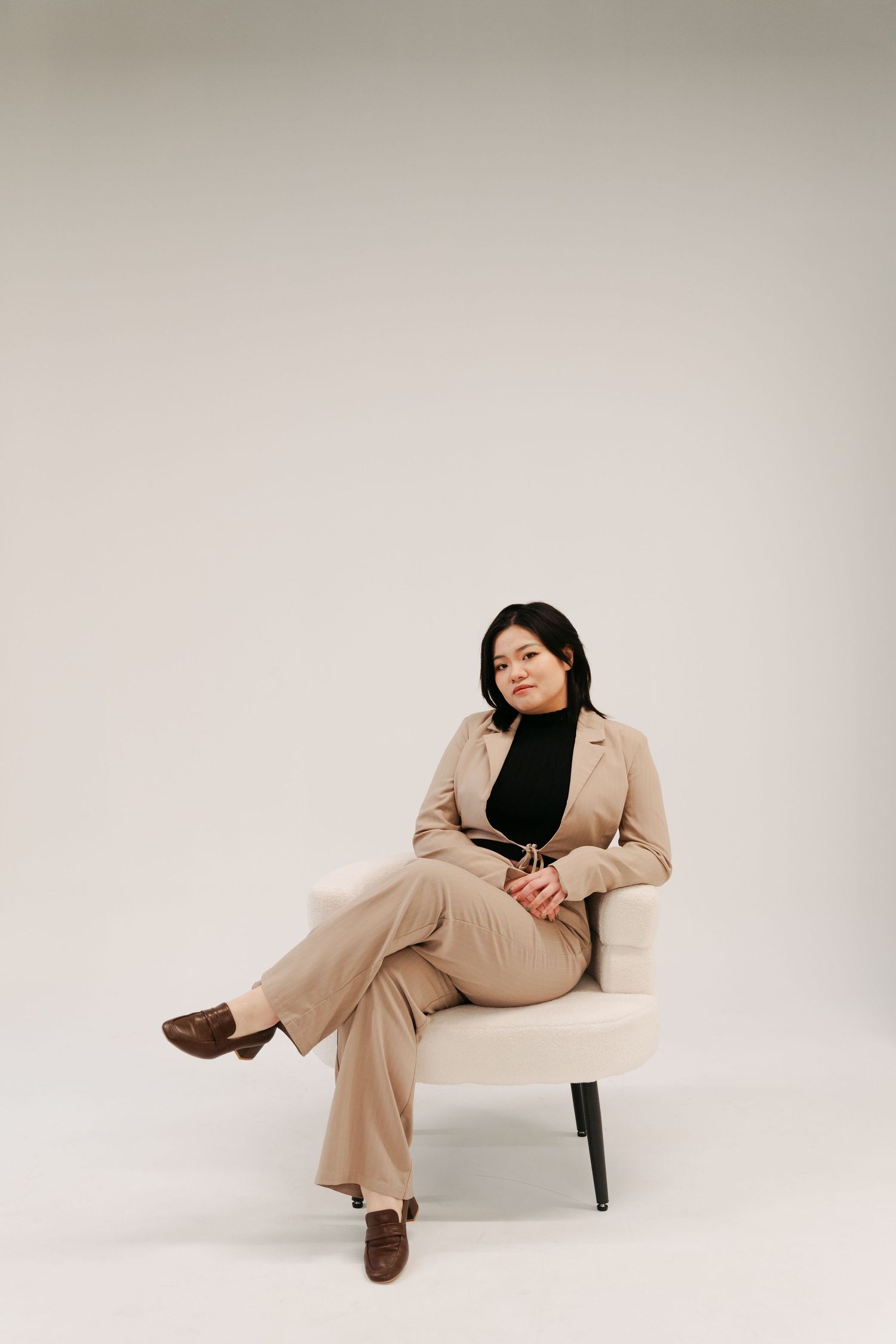 A series of fashion photos showing a person in a beige pantsuit lounging on white furniture against a light background in Halifax, NS.
