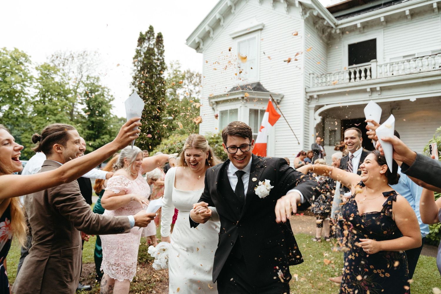 Wedding guests shower newlyweds with confetti during joyful outdoor celebration at elegant venue in Halifax, Nova Scotia.