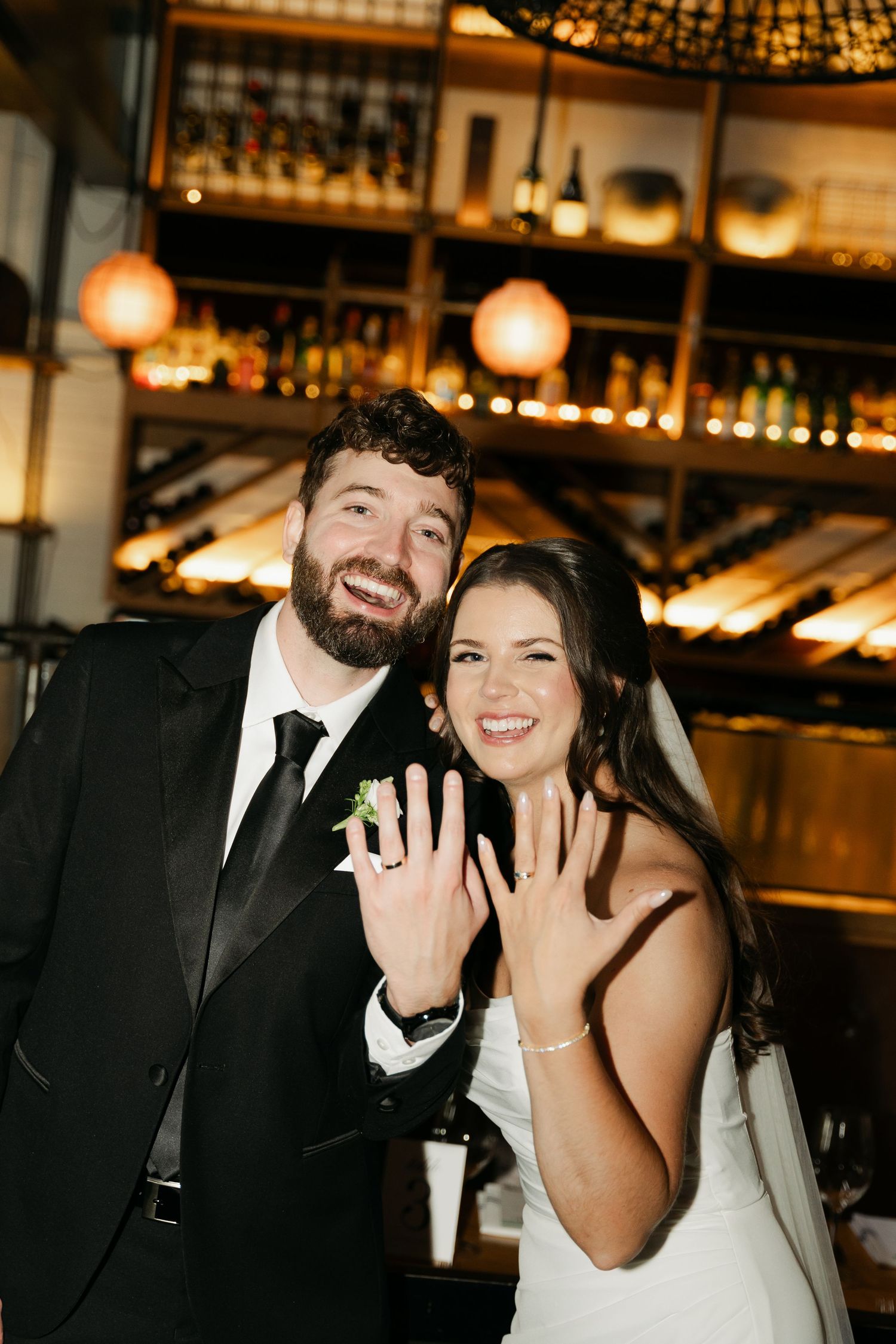 A joyful wedding couple shares candid moments together in a warmly lit indoor venue in Halifax, Nova Scotia.