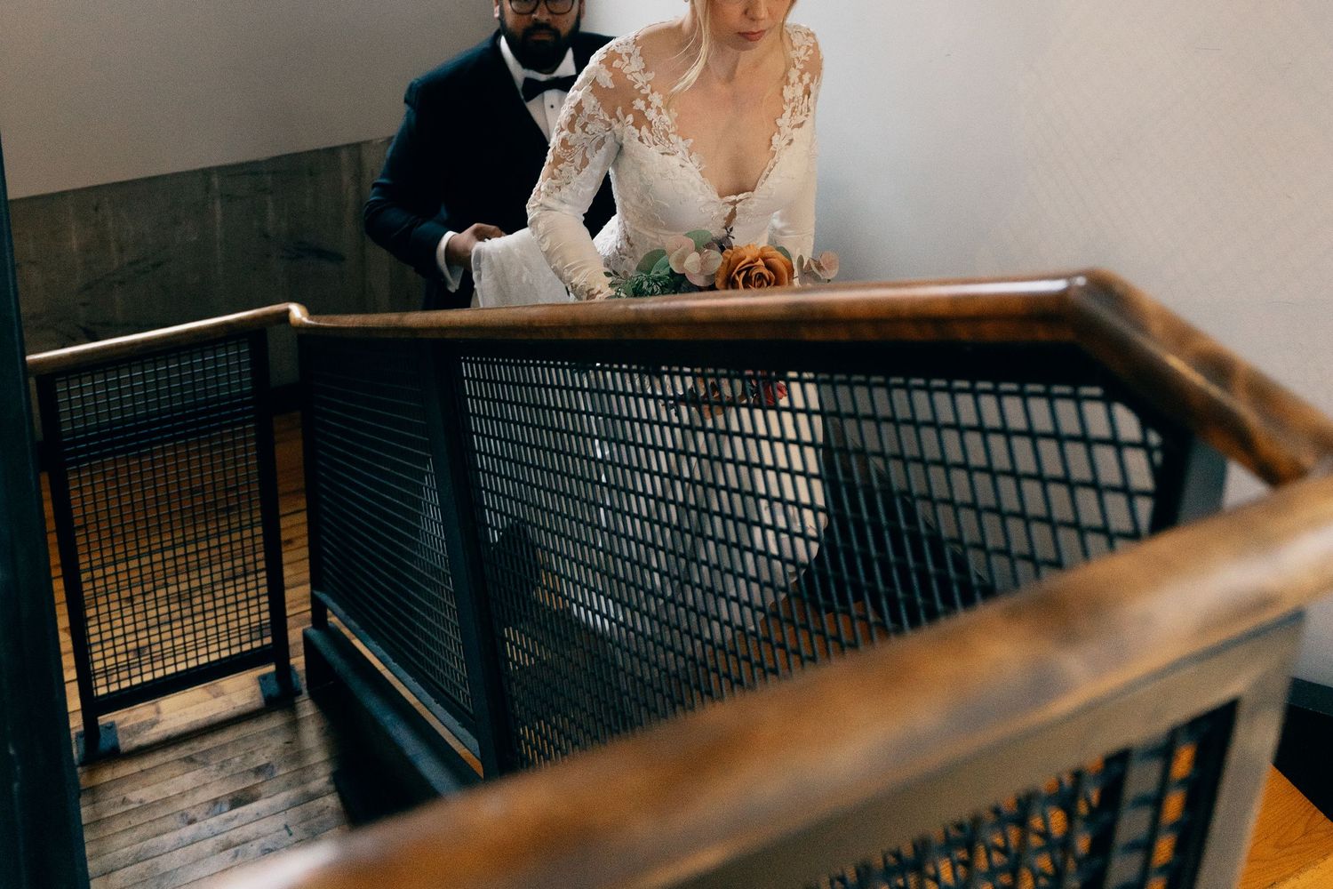 Couple in formal wedding attire seen from above on industrial-style staircase at Lightfoot & Wolfville.