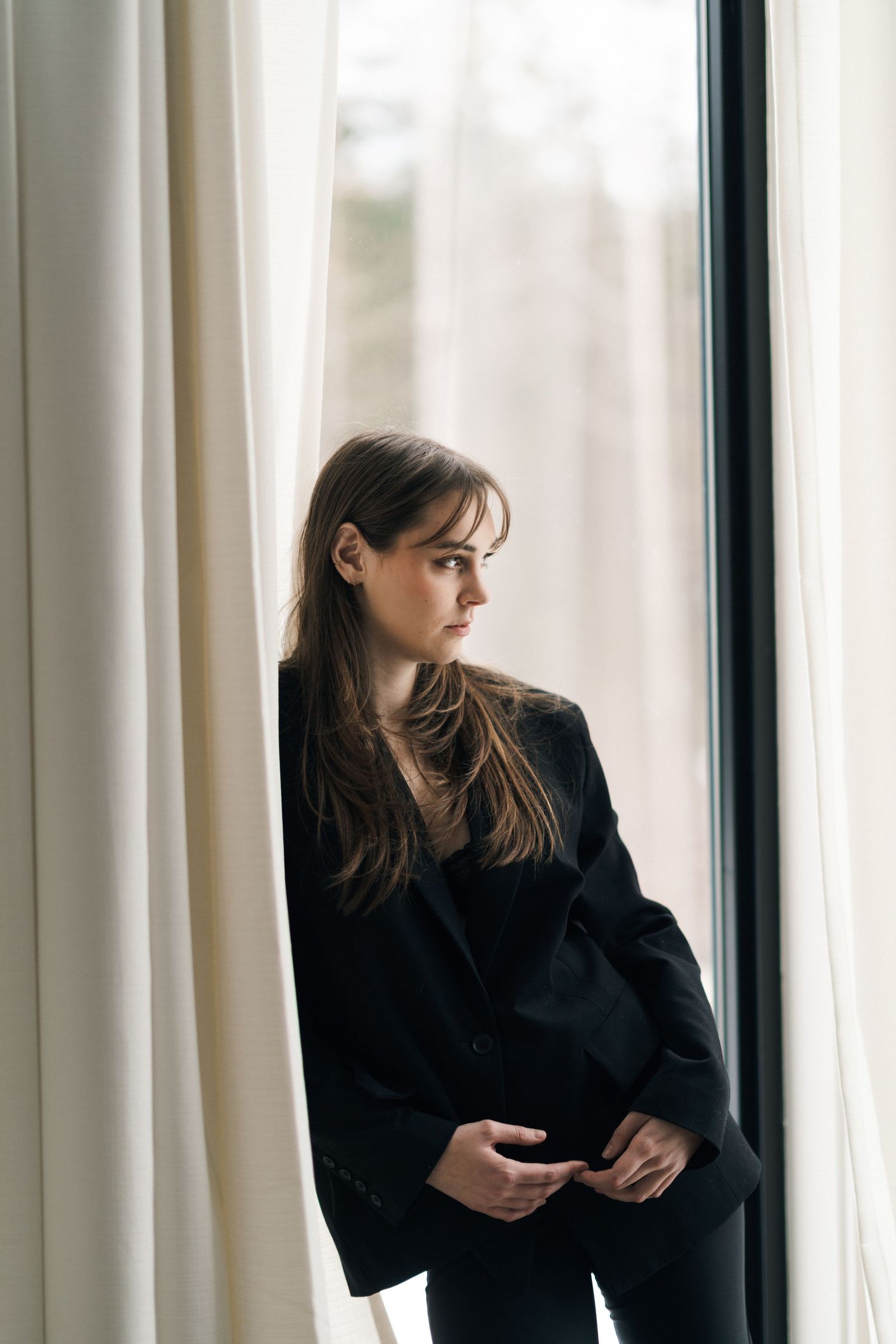 Moody window portraits showing contemplative poses against white curtains and natural light in Halifax, Nova Scotia.