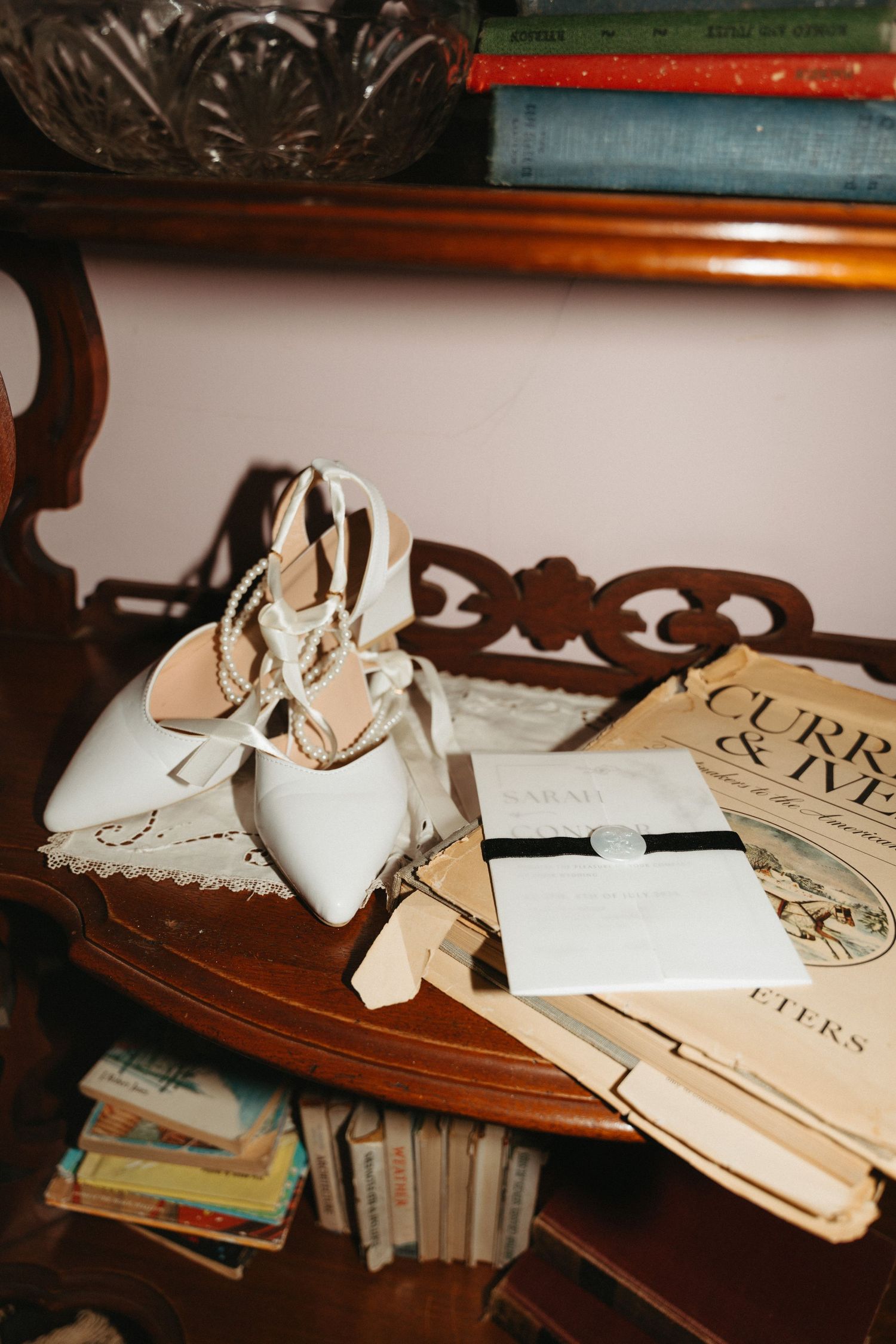 Vintage white wedding shoes displayed with antique books on wooden table in Halifax, Nova Scotia.