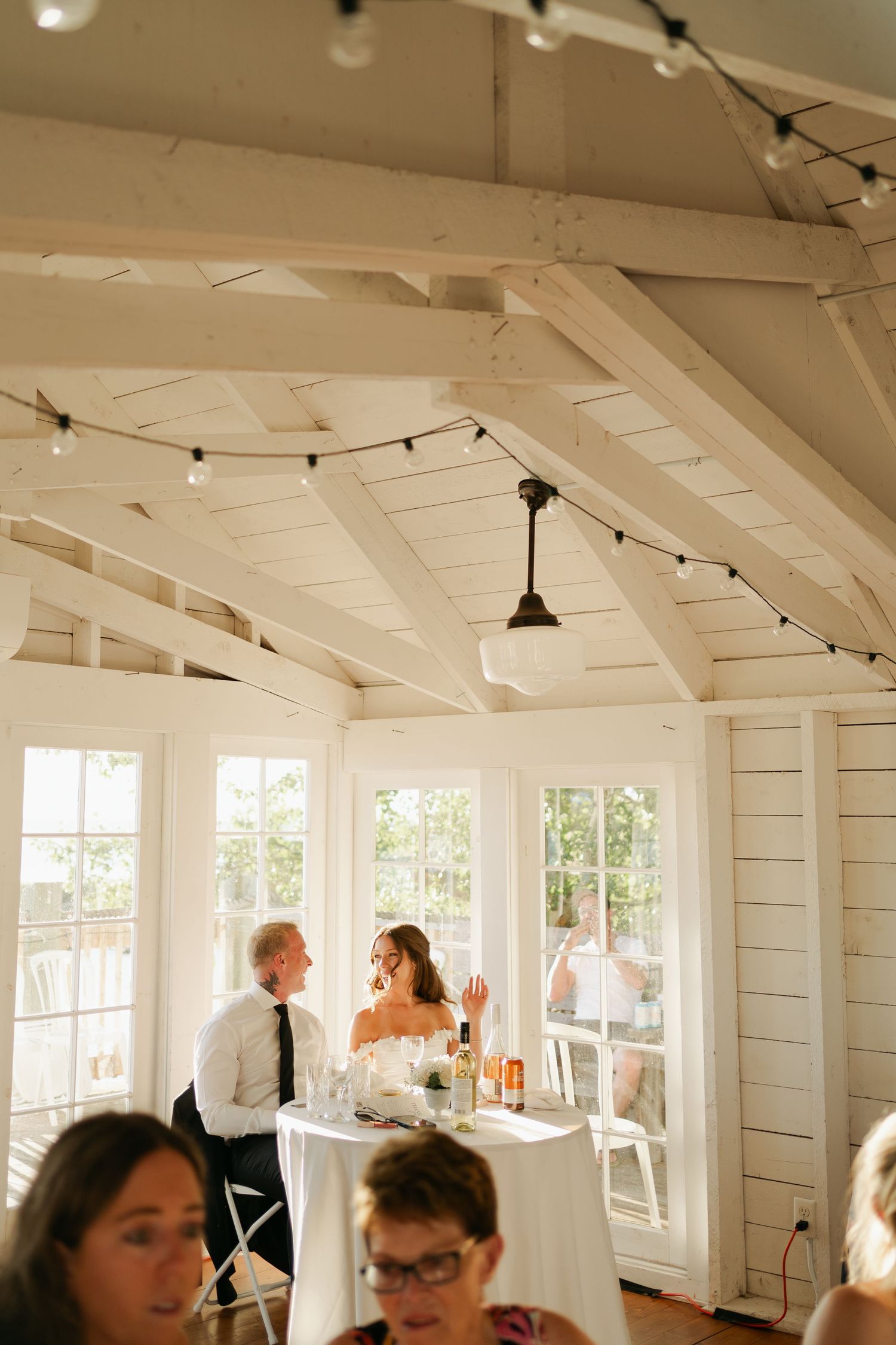 A bright white indoor venue with string lights and windows hosts a gathering of people in a casual setting in Halifax, Nova Scotia.