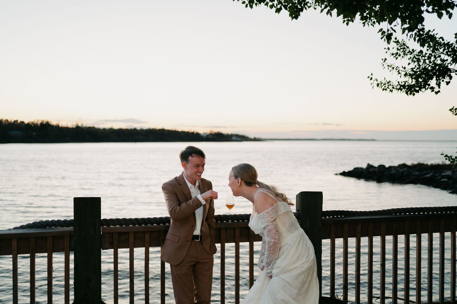Romantic waterfront wedding scene at sunset with wooden deck railing in Nova Scotia.