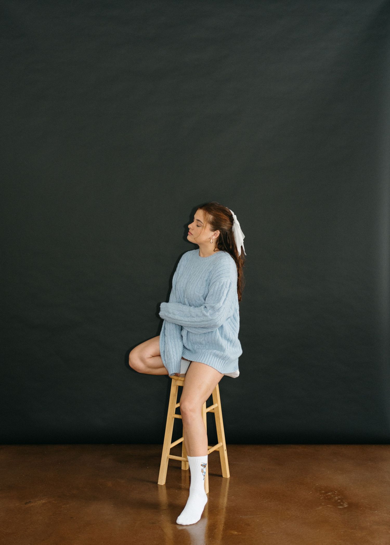 A sequence of artistic poses on a wooden stool against a dark backdrop showing movement in casual blue attire in Halifax, Nova Scotia.