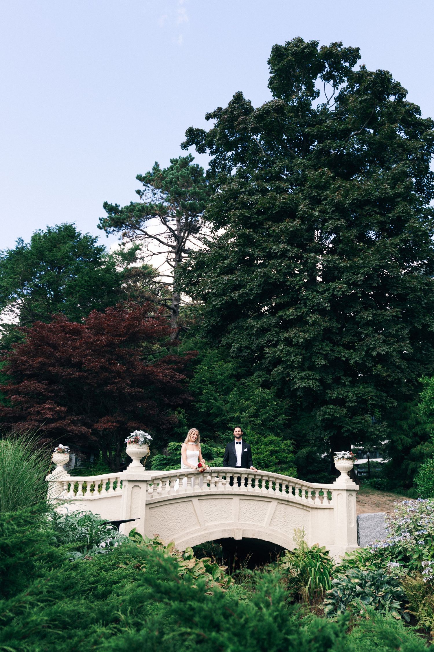 A decorative white stone bridge in a lush garden setting under blue sky in Halifax, Nova Scotia.