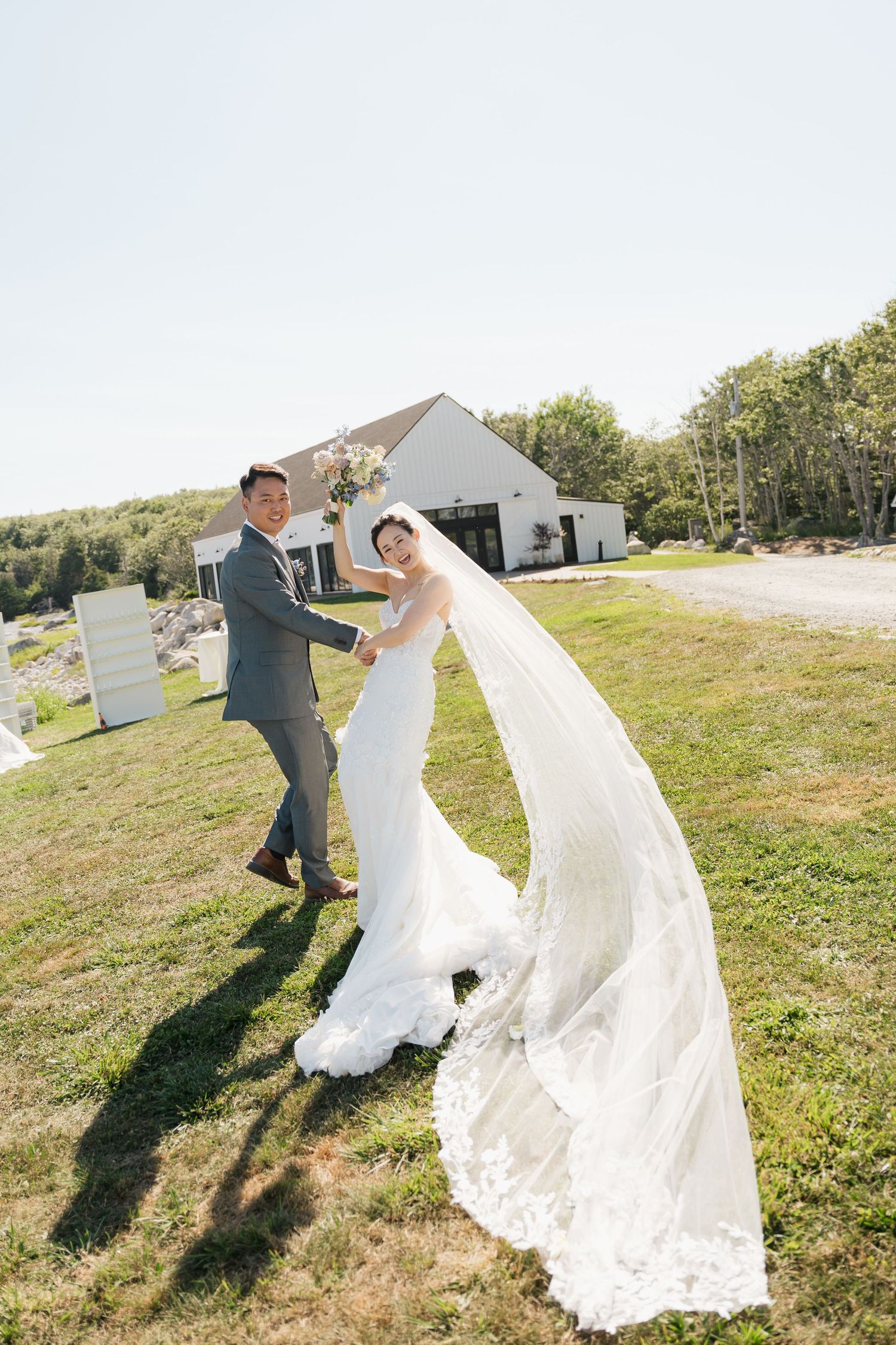 Wedding couple dancing and twirling on a grassy hilltop with flowing white dress in Halifax, Nova Scotia.
