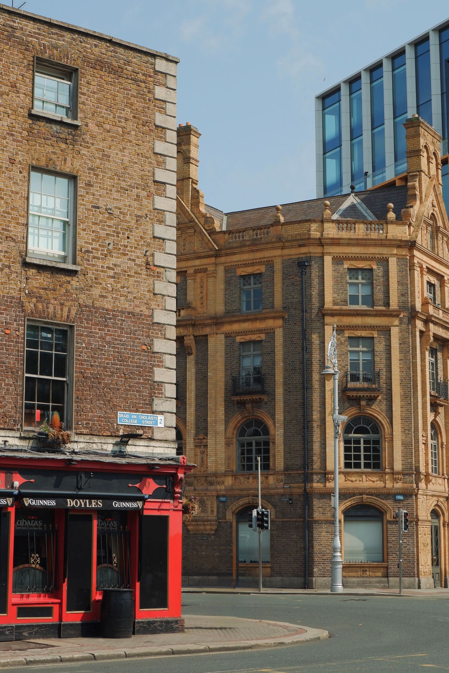 Historic brick buildings in Glasgow with red storefront pub and ornate Victorian architecture on street corner.