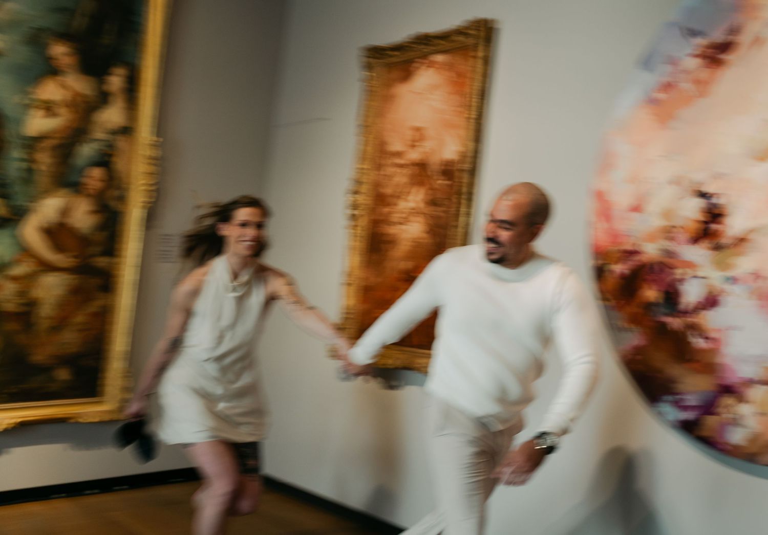 A series of blurred motion photographs showing people walking through an art gallery in Montreal, Quebec with paintings on the walls.