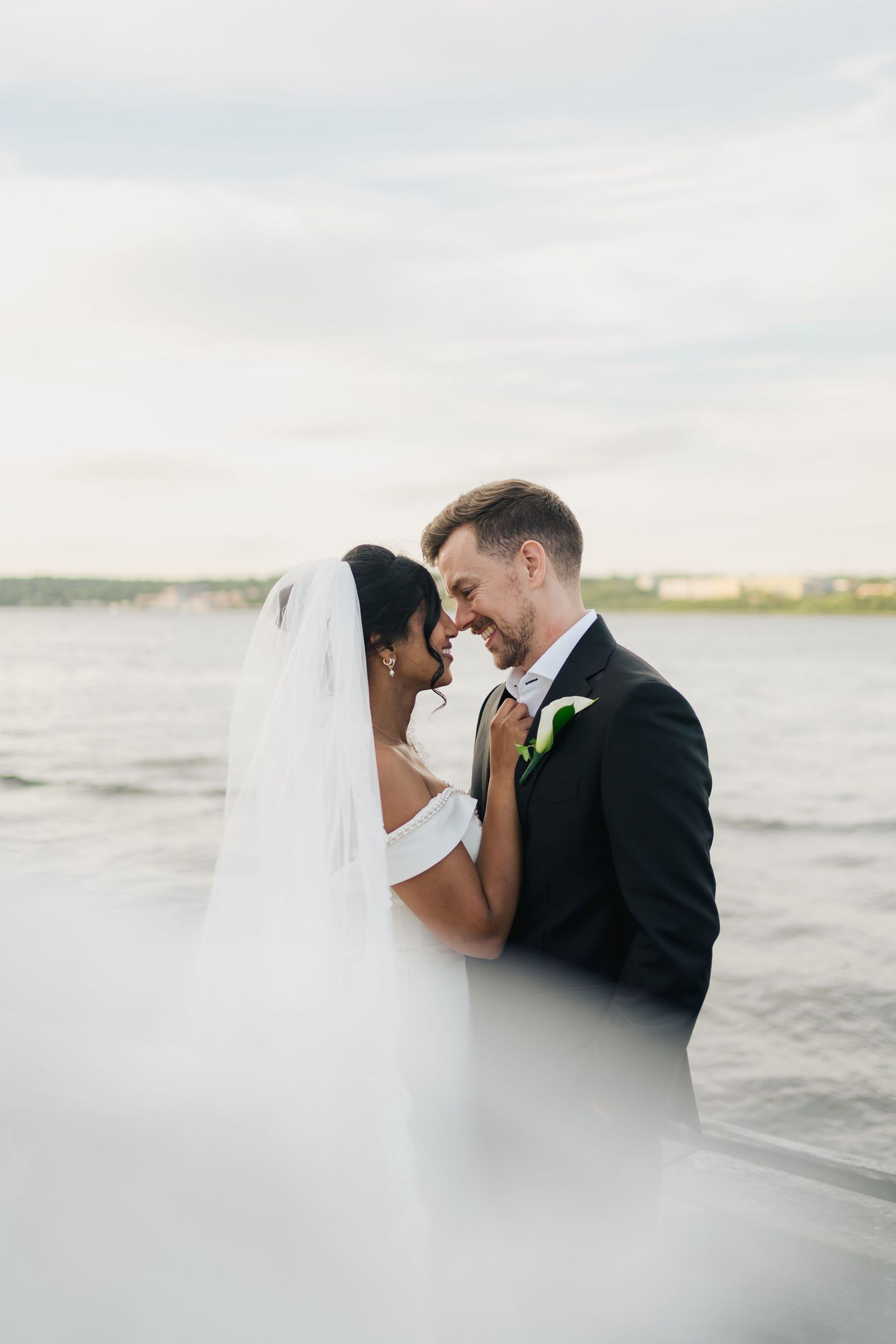 A romantic seaside wedding photoshoot showing a couple in formal attire embracing against an ocean backdrop in Halifax, Nova Scotia.