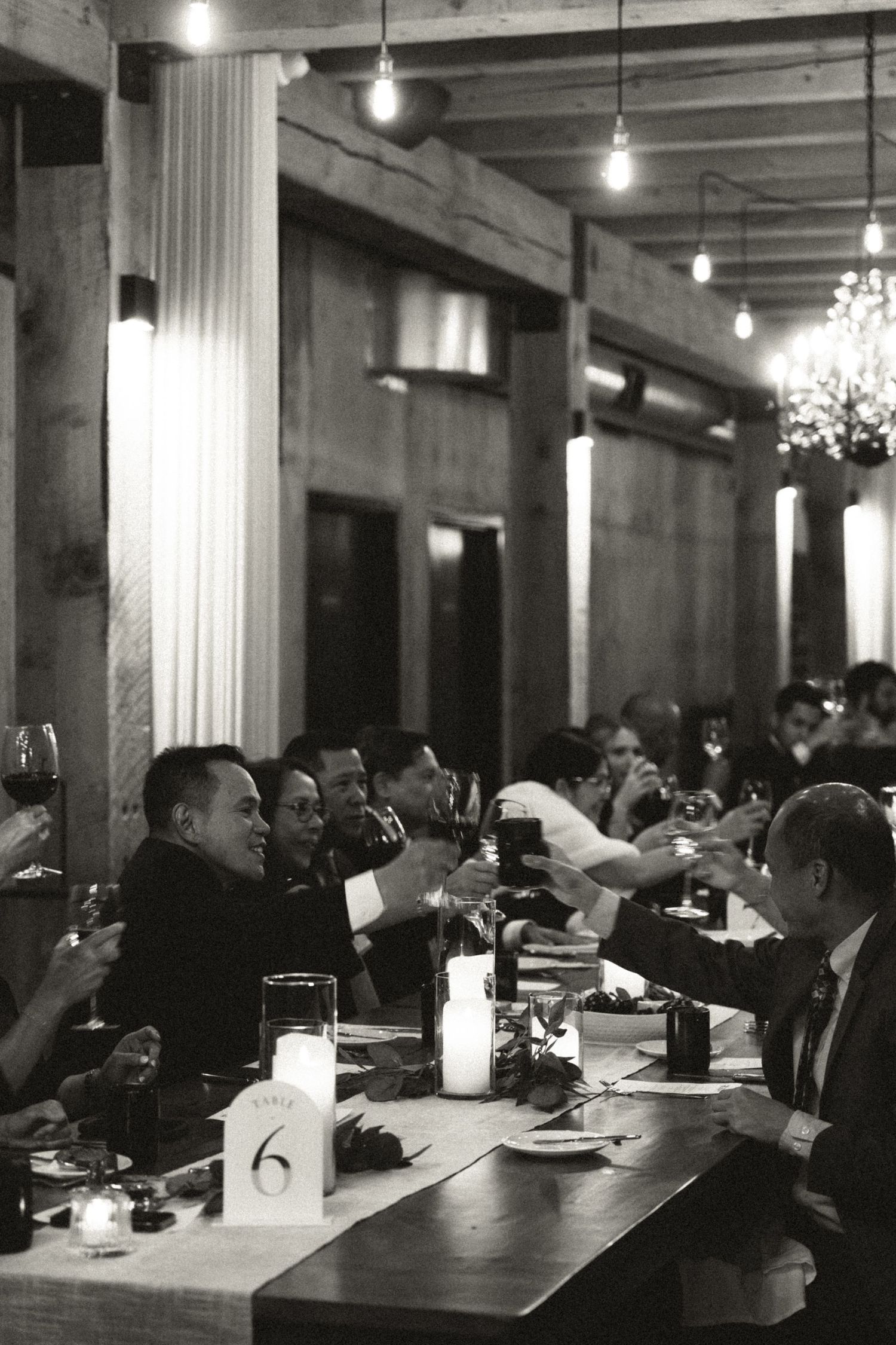 A dimly lit restaurant interior with diners seated at tables under hanging chandeliers and white columns in at Lightfoot & Wolfville
