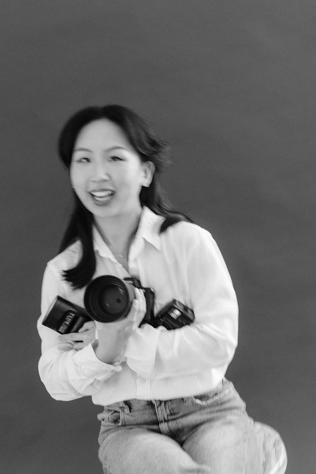 A black and white photo series showing someone in a white shirt posing playfully against a dark background.