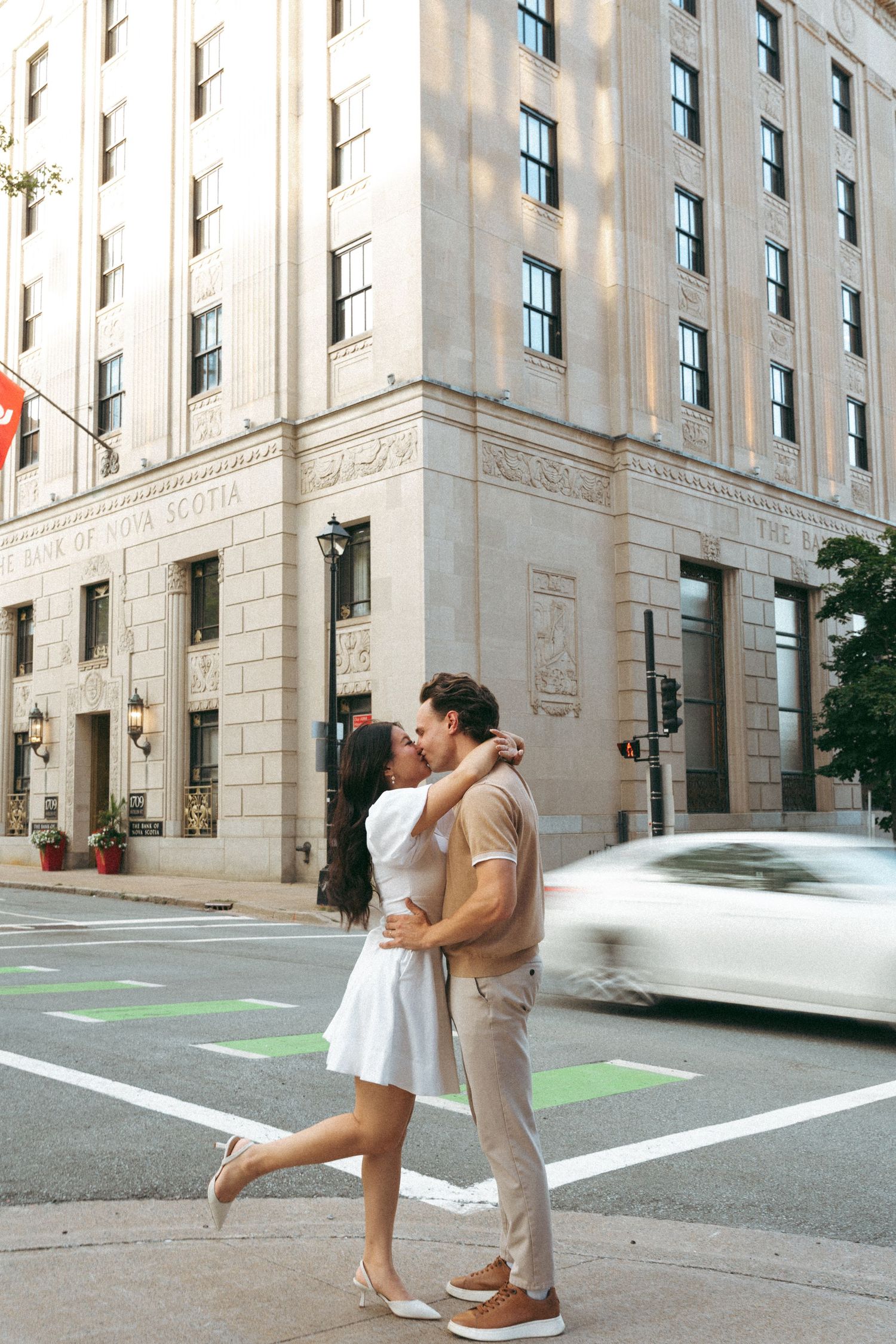 Couple dancing and embracing in an urban courtyard with tall stone buildings in the background in downtown Halifax, Nova Scotia..