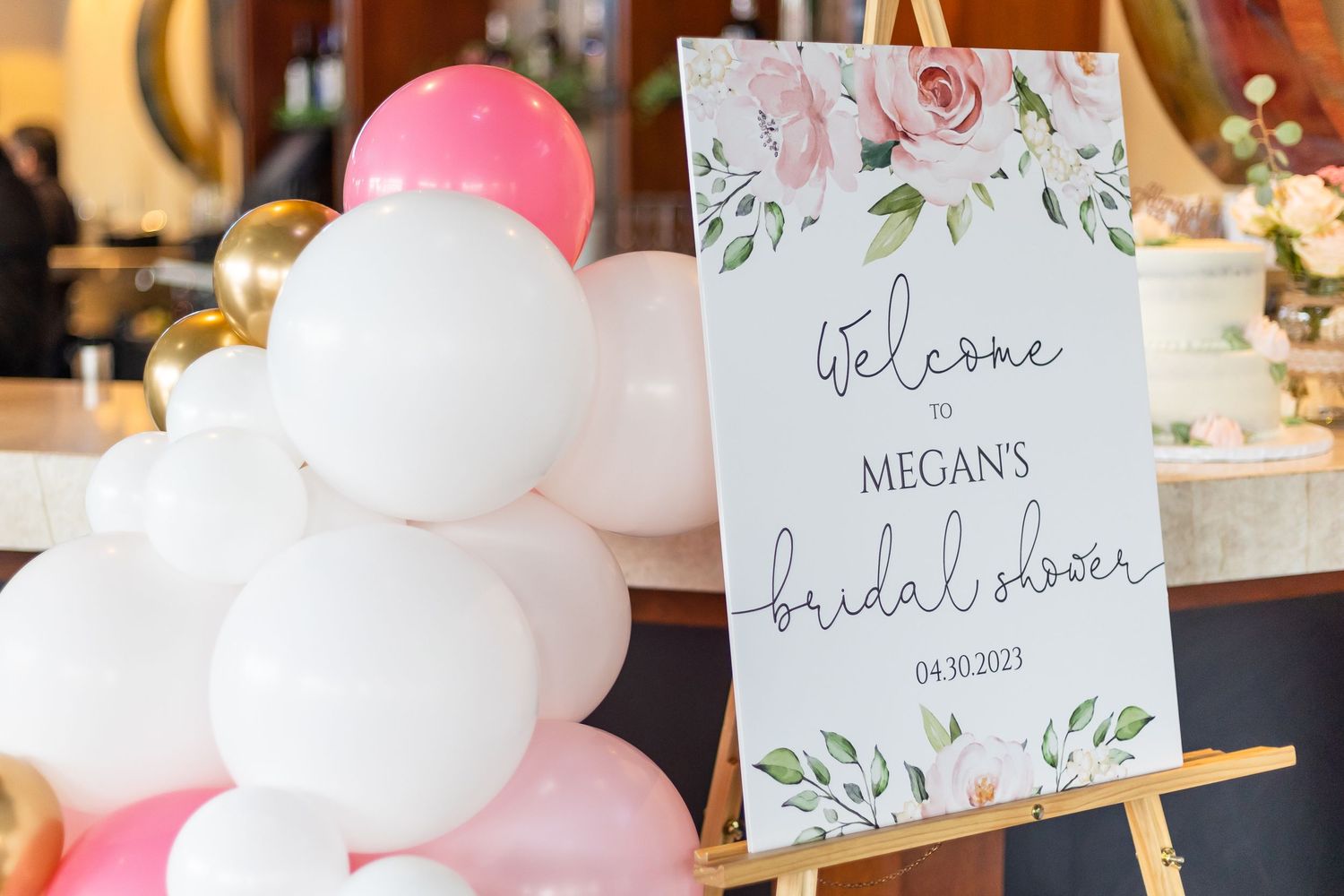 Welcome to Megan's bridal shower sign on easel with pink and white balloon arrangement.