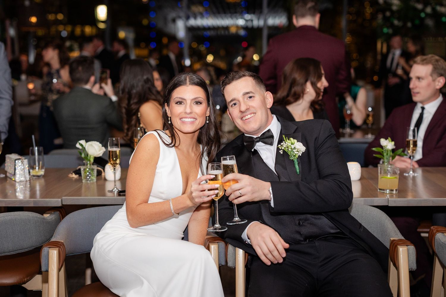 Bride and groom toasting champagne flutes together at wedding reception dinner.