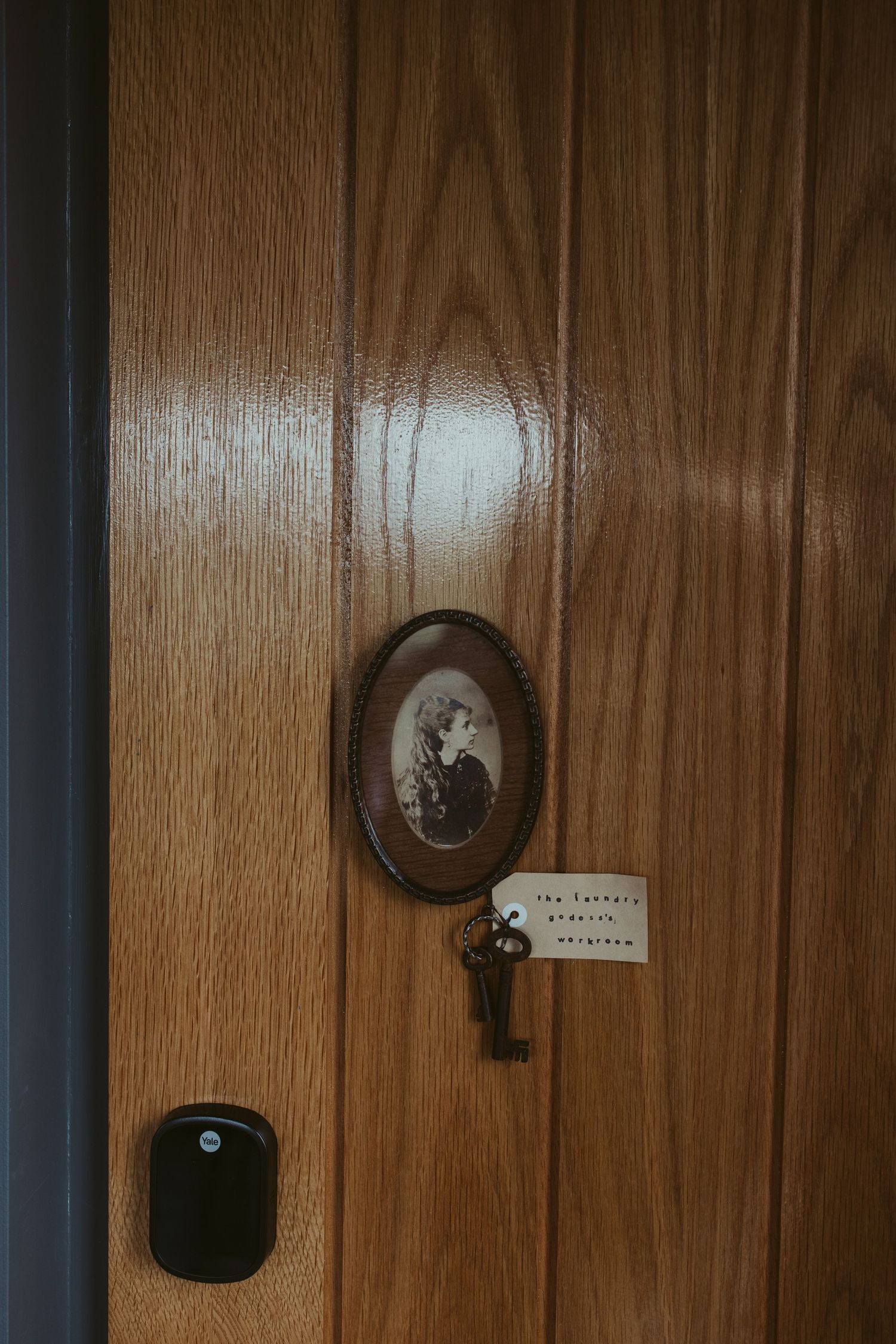 Vintage wooden door with antique oval portrait frame and old skeleton key with tag attached.