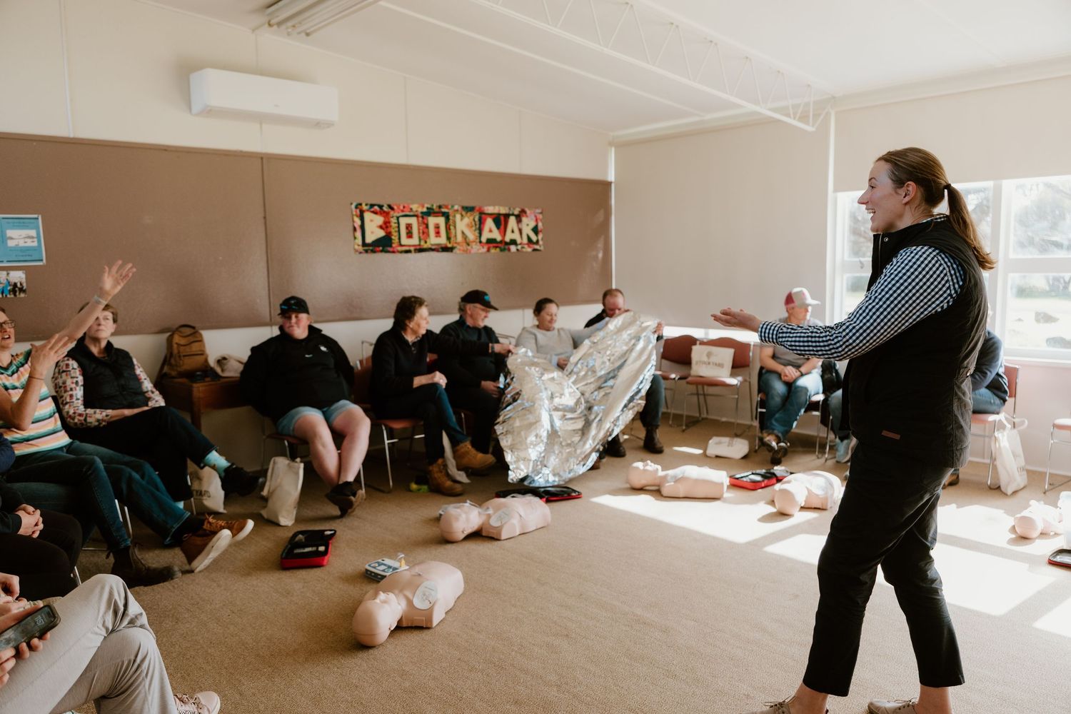 First aid instructor teaching CPR techniques to a group of attentive adults in a cozy community room.