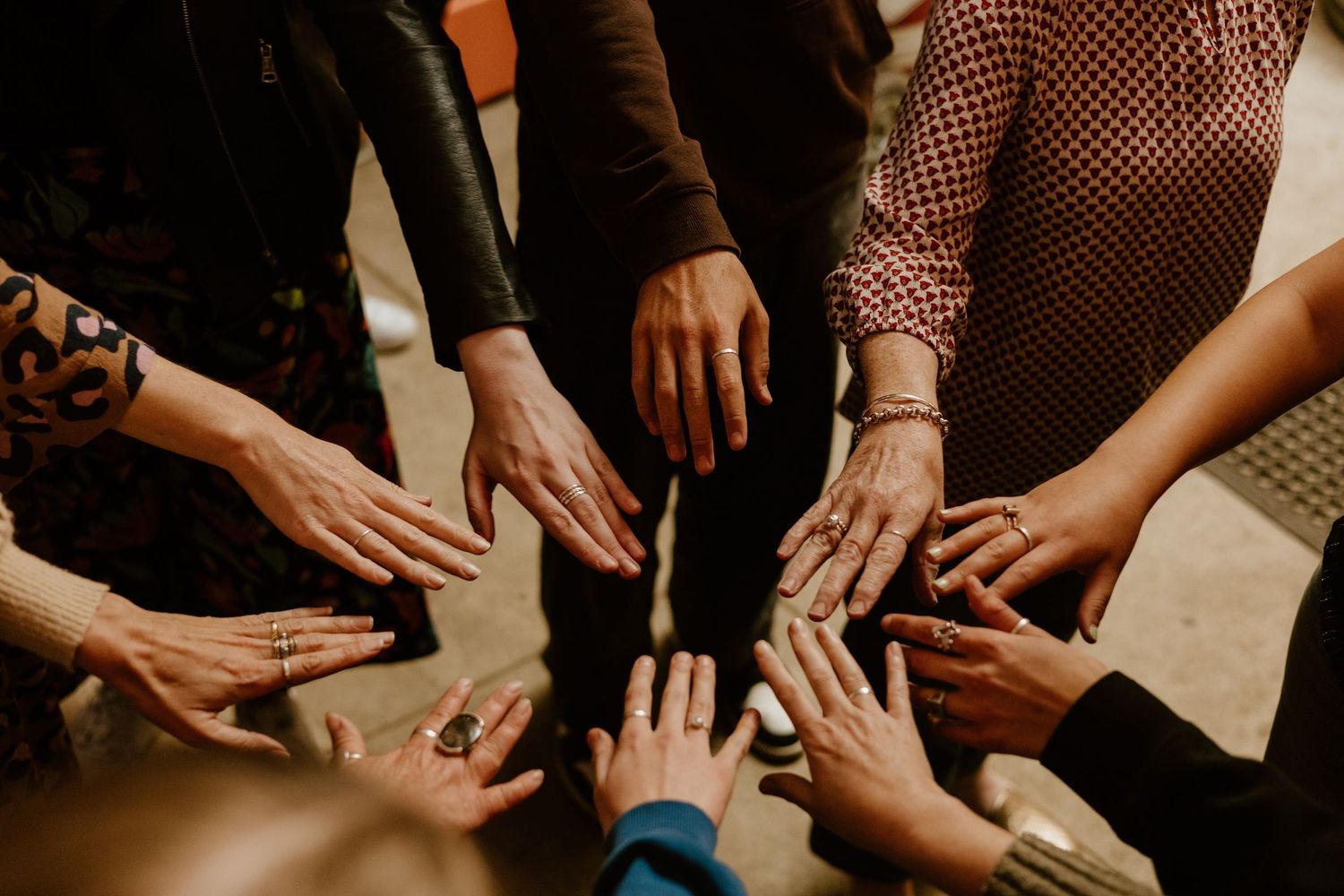 Diverse group of people joining hands together in a circle, symbolizing unity, teamwork, and collaboration.