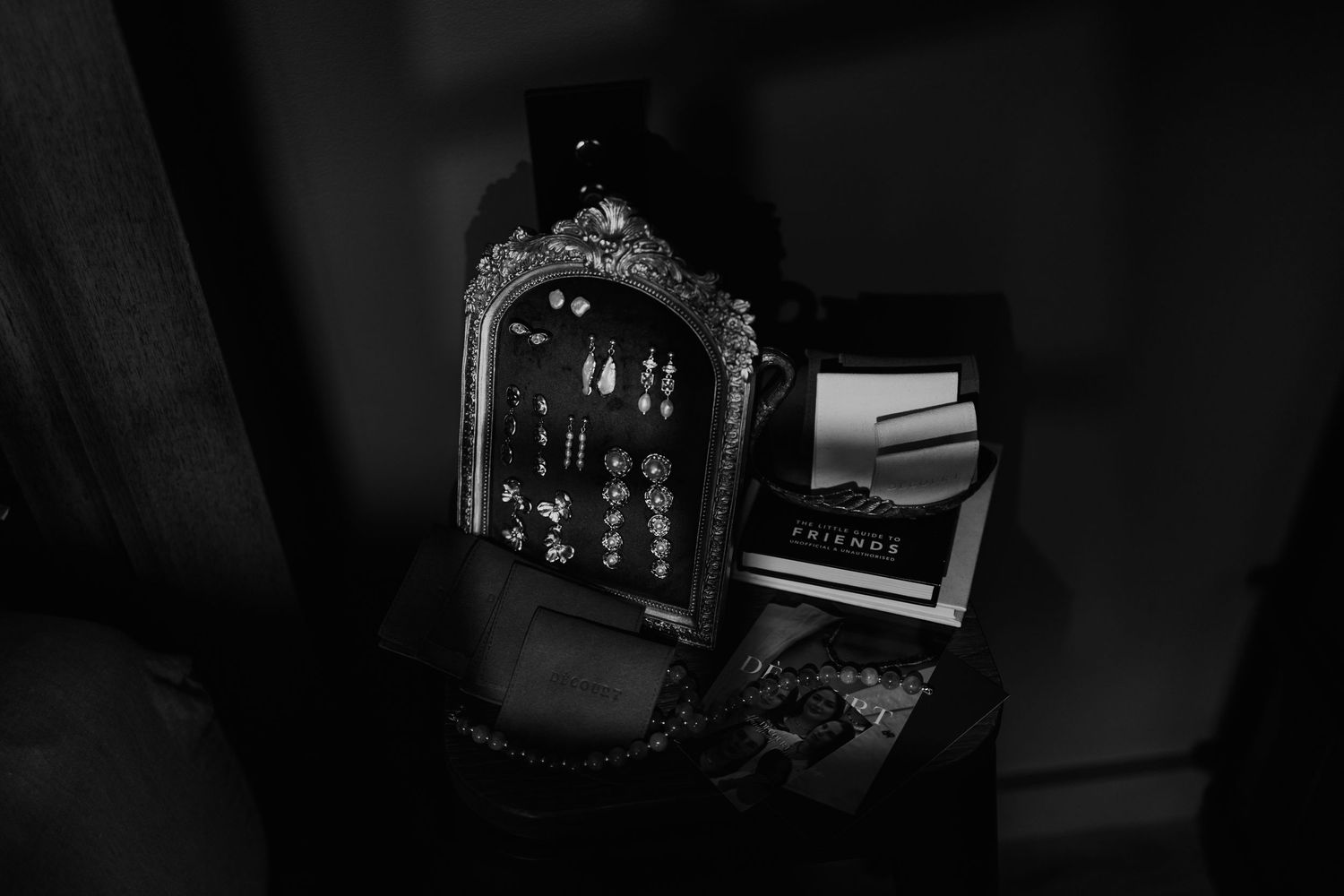 Black and white photo of wedding jewelry and accessories on dark surface.