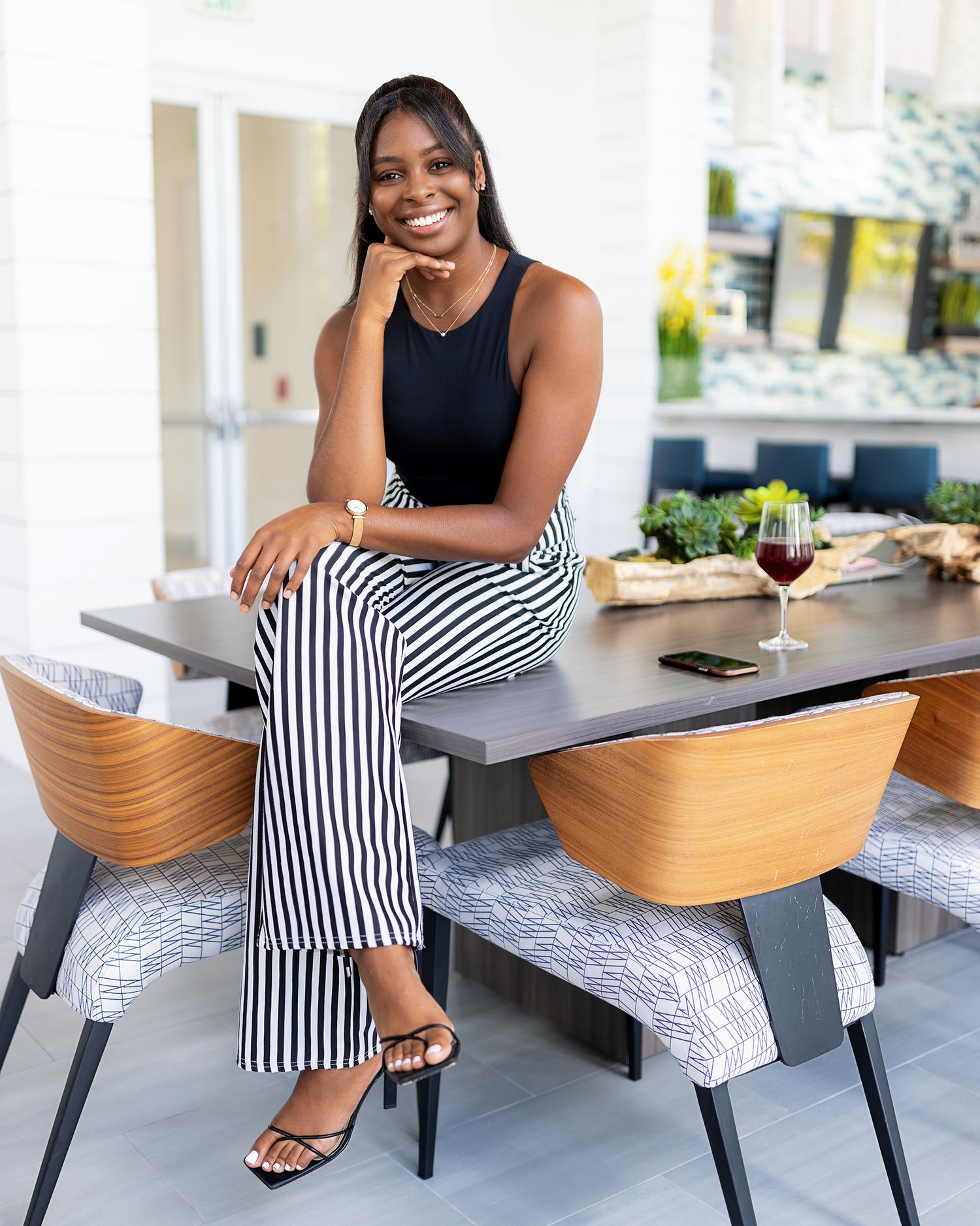 Black women entrepreneur on table. Female chef and meal preps. Glass of red Wine and stripped black and white pants.