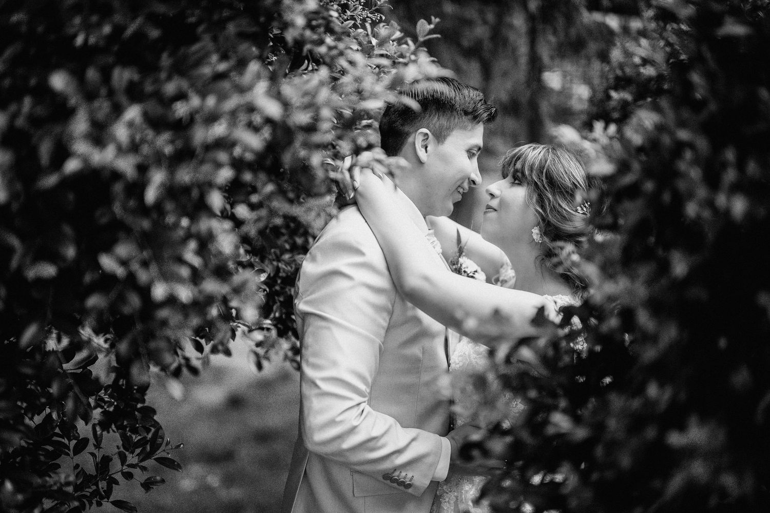 Black and white wedding photograph showing couple dancing together in an intimate garden setting.
