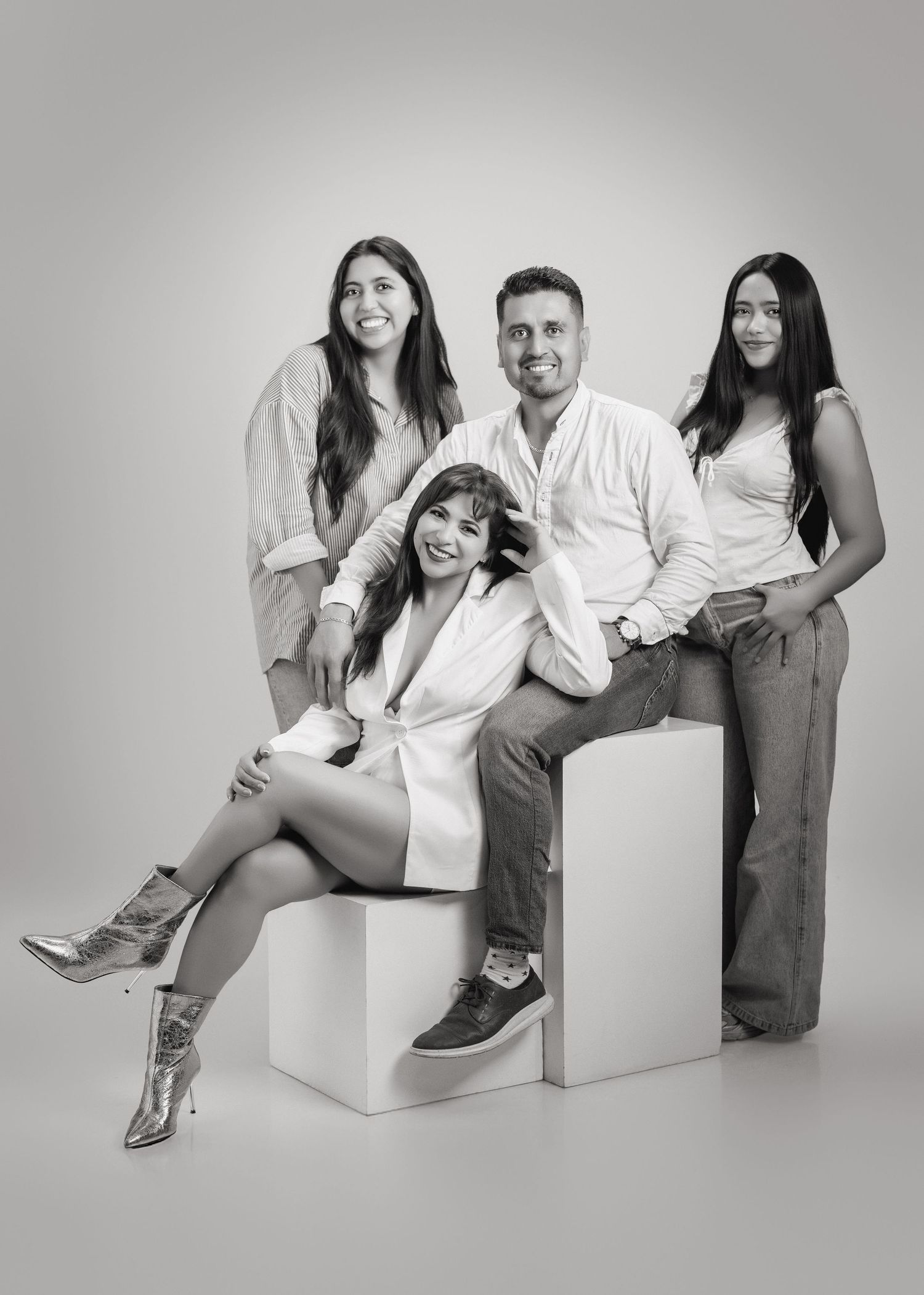 A series of black and white studio photos showing playful poses with people sitting and interacting on white blocks.