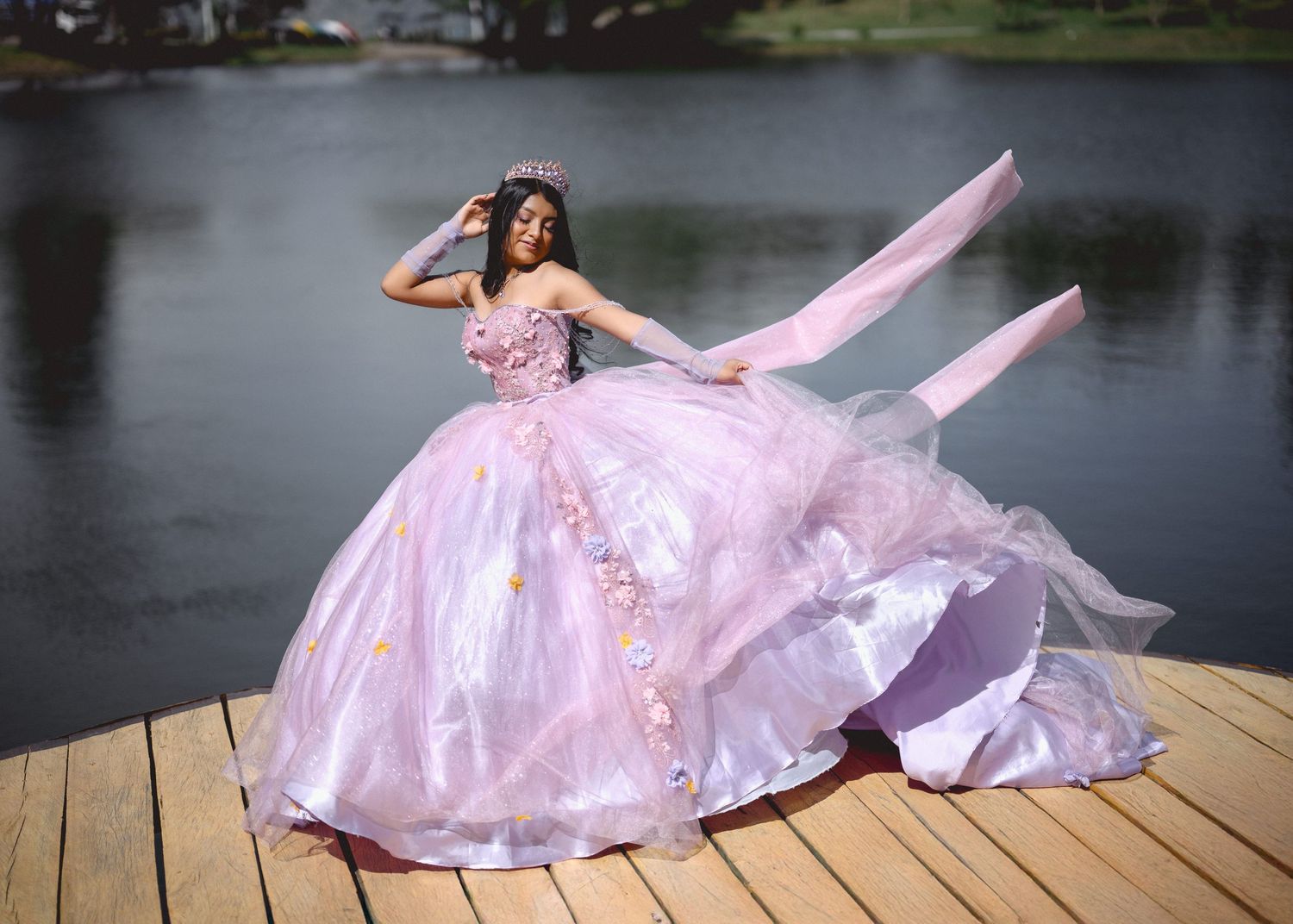 A flowing pink gown creates a graceful movement sequence across wooden dock panels by a serene lake.