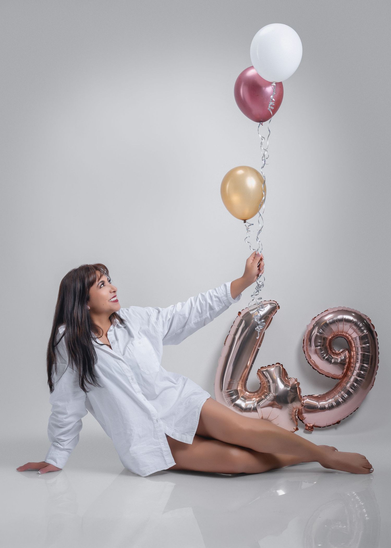 A series of four artistic portraits showing a figure in a white shirt posing with silver number balloons and colorful balloons.