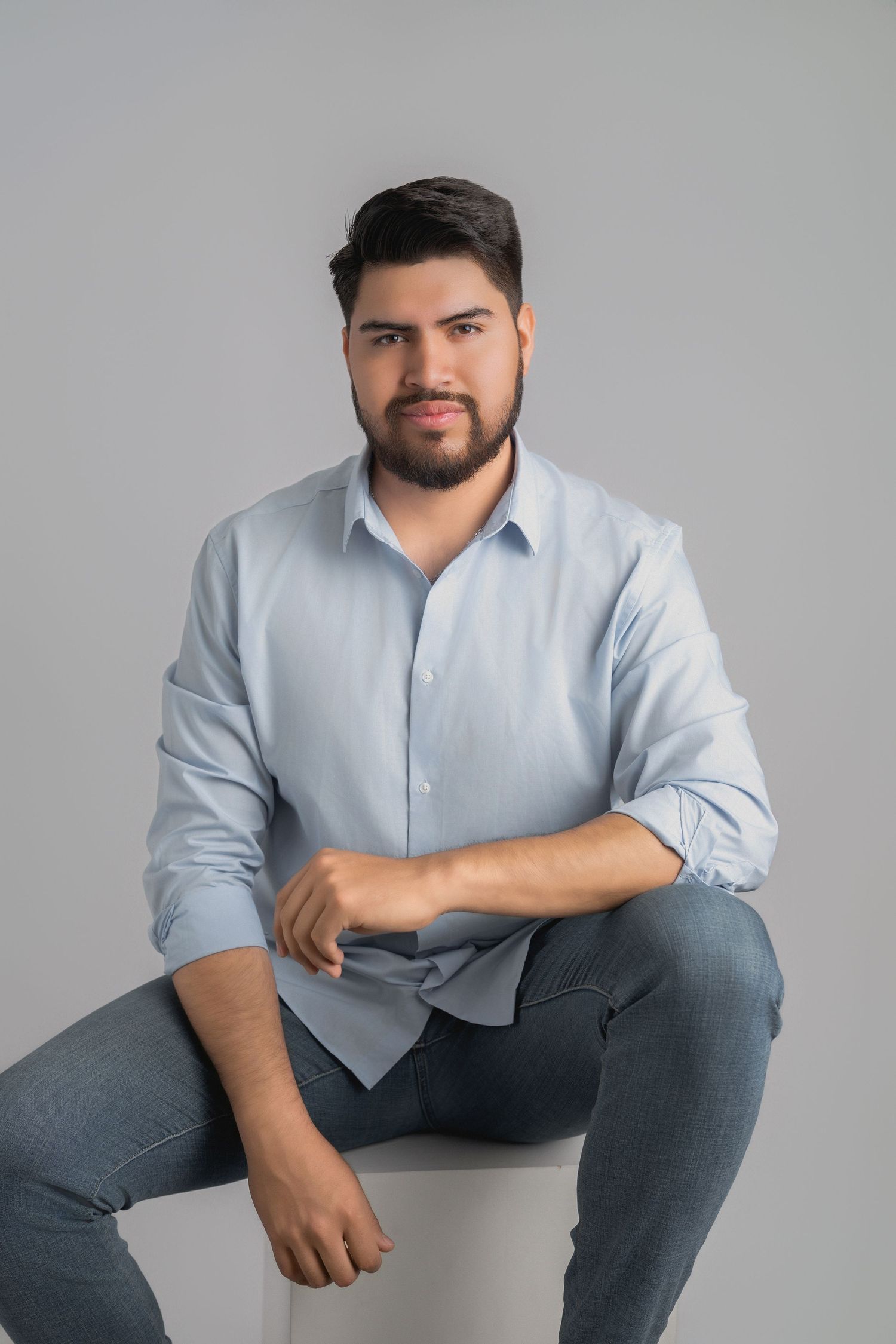 Professional studio portrait of someone wearing a light blue button-down shirt and gray pants in various casual poses.