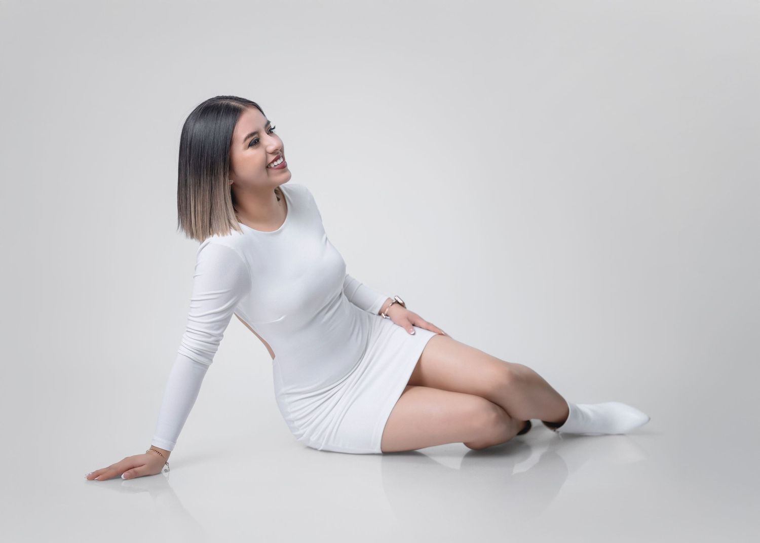 A person in white clothing lies on a white floor in various graceful poses creating a minimalist artistic composition.