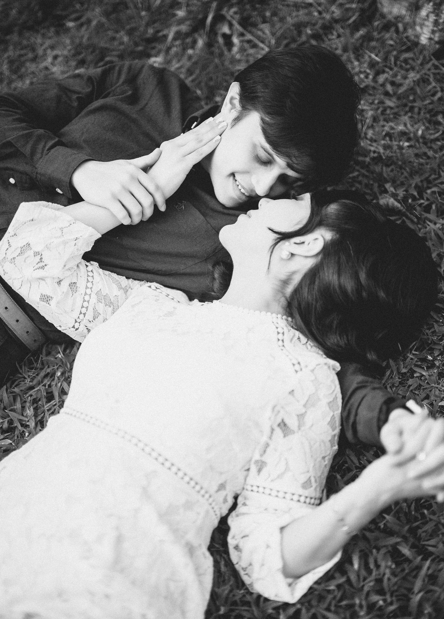 A couple lying on grass in black and white, shown in a series of romantic poses.