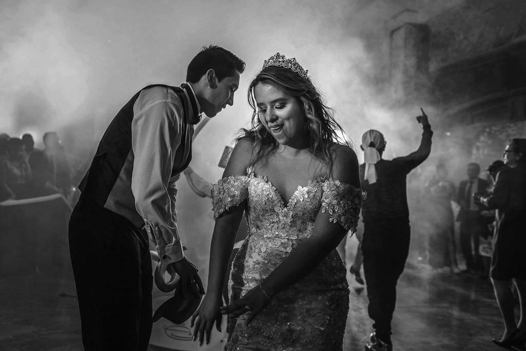 Black and white photo of wedding guests dancing on a misty dance floor.
