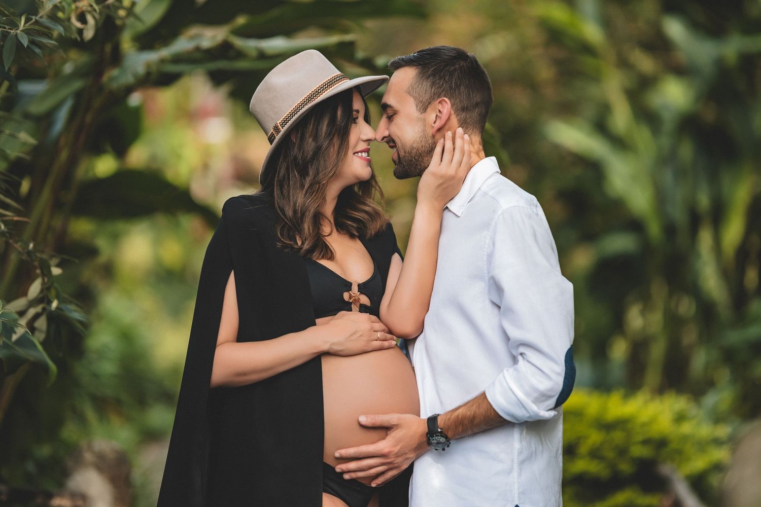 A couple shares romantic moments in a lush garden setting during a photo session.